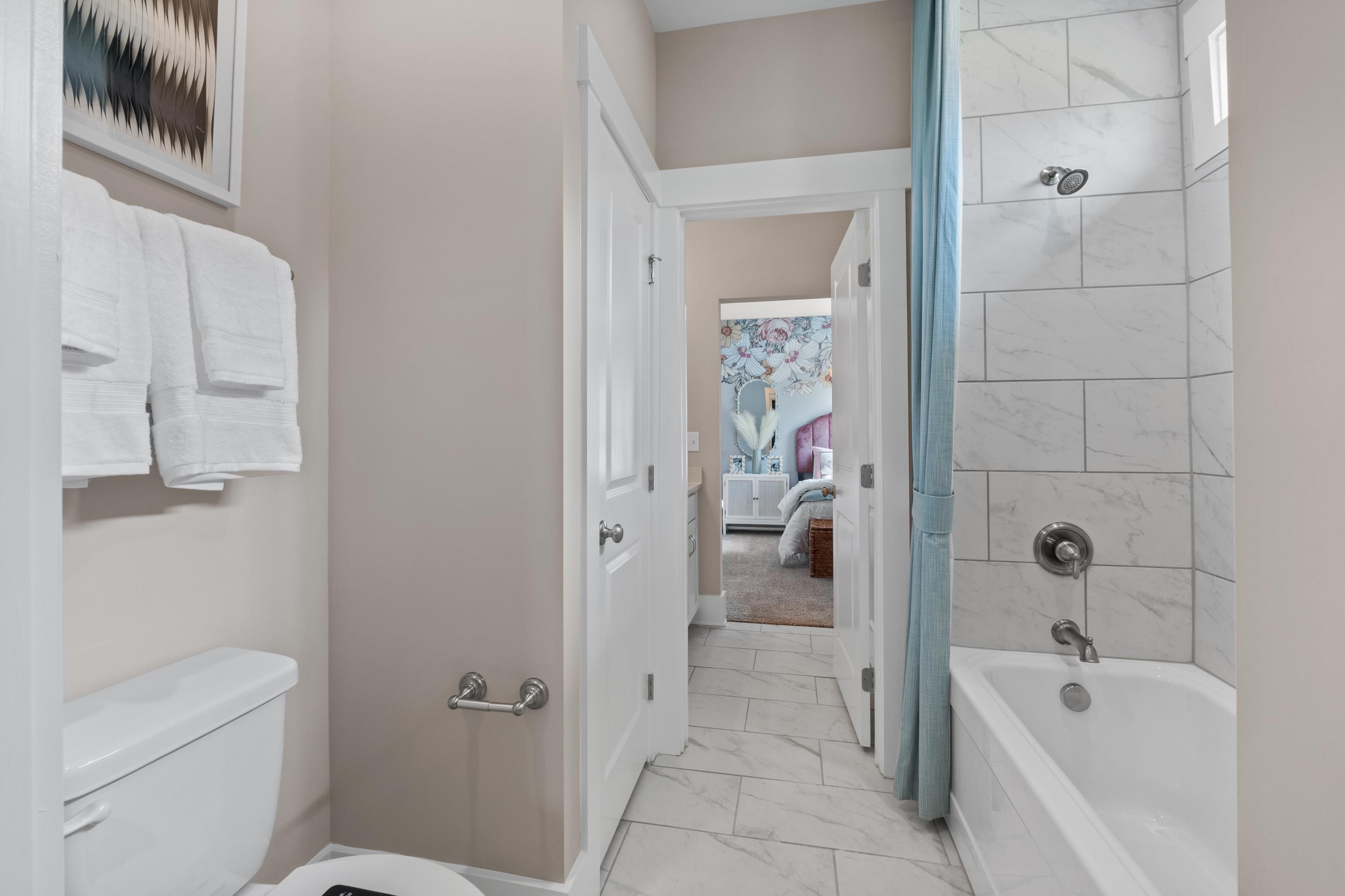 Spacious master bathroom at Creekside in Harvest Alabama with white subway tile, soaking tub, and bedroom view