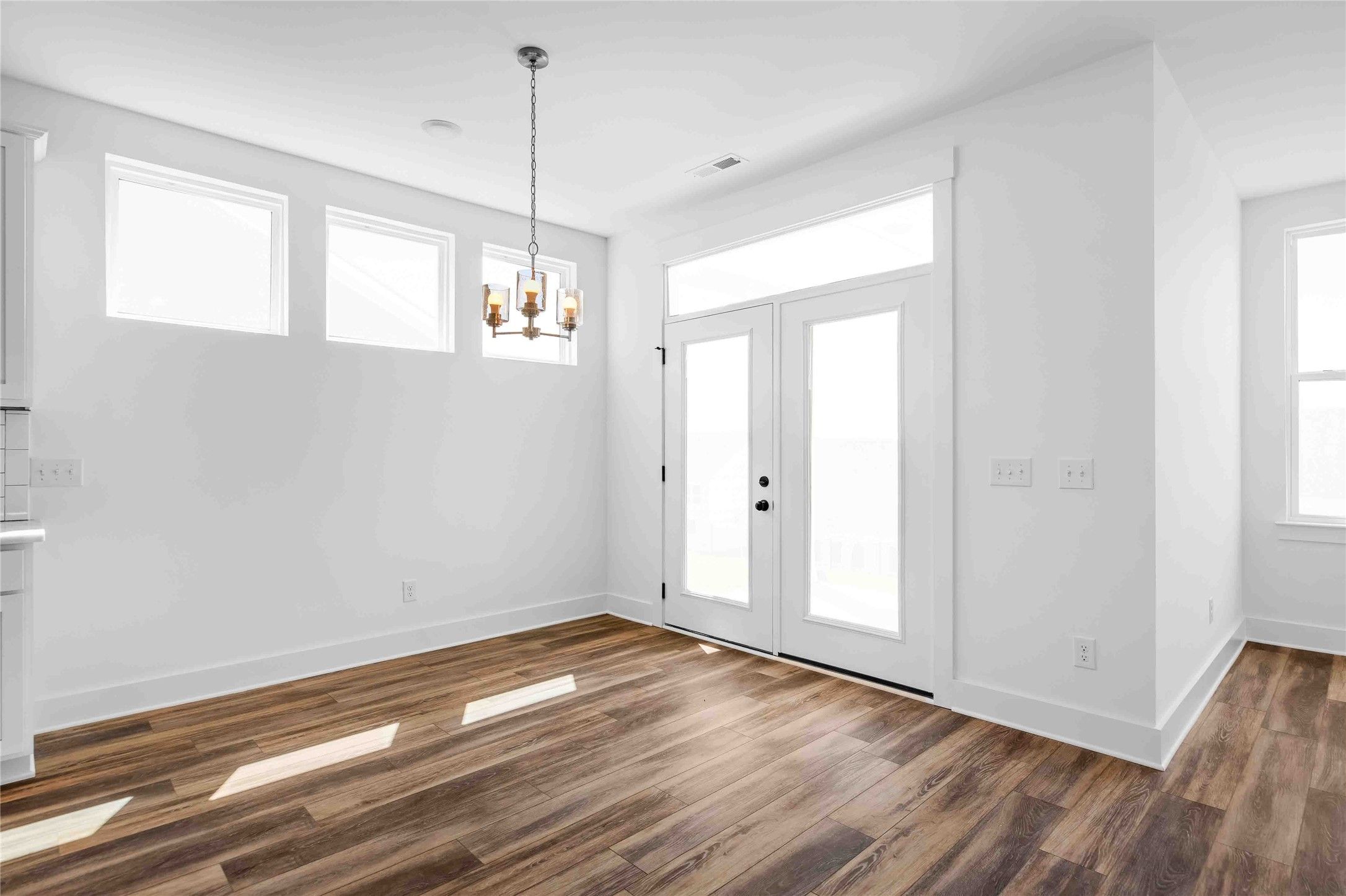 Bright dining area with wood-look flooring and glass patio doors in The Ash O floor plan by Davidson Homes in Heartland.