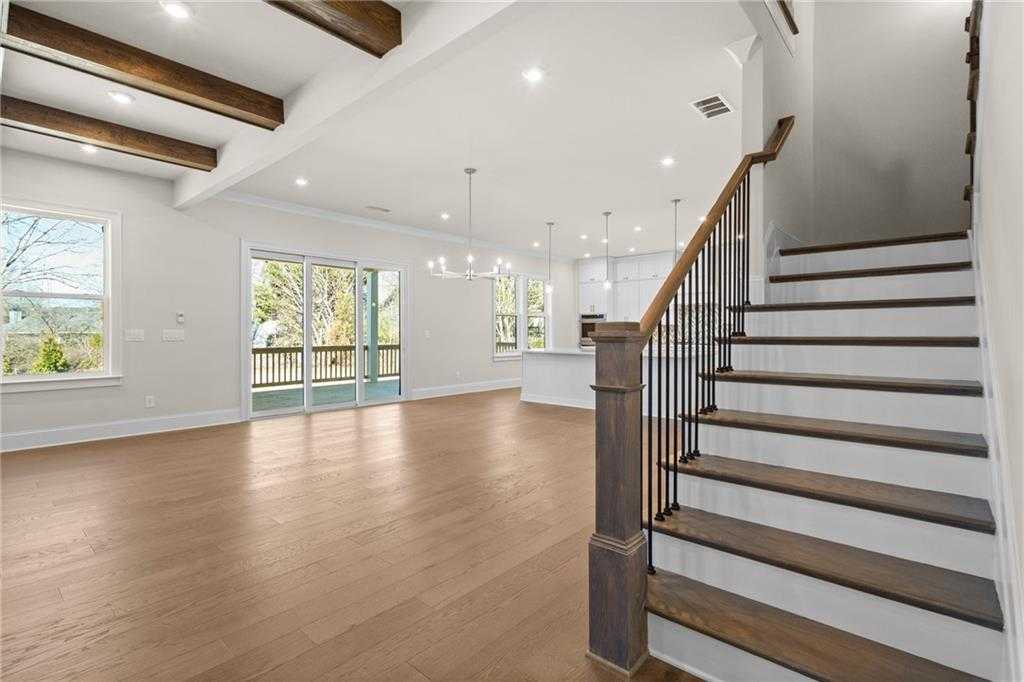 Open great room with hardwood floors, exposed beams, wrought-iron staircase, and sliding doors to deck in Davidson Homes The Arlington A, East Cobb
