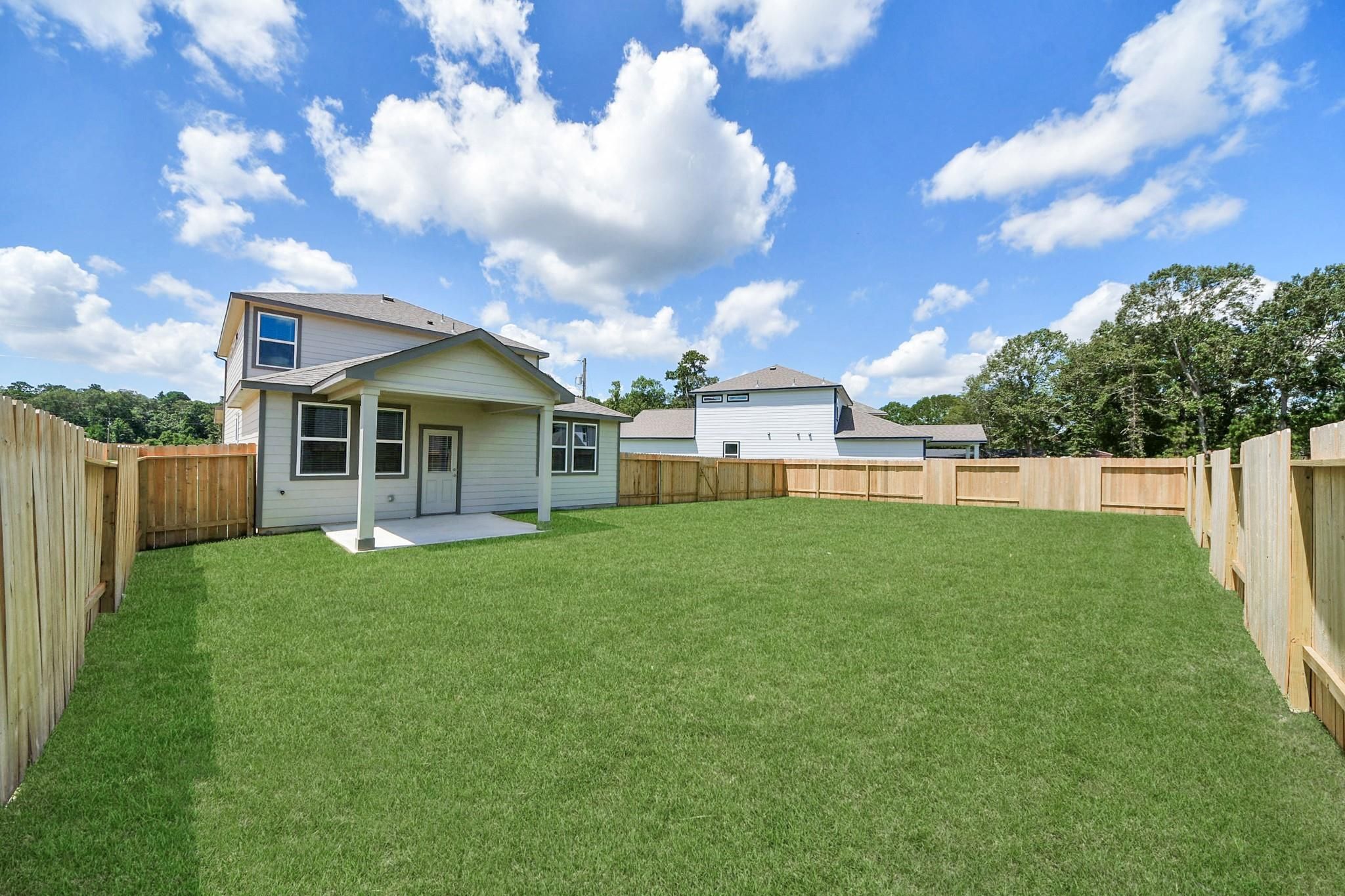 Fenced private backyard with covered patio at The Brazos F home in Liberty Estates, Cleveland, Texas.