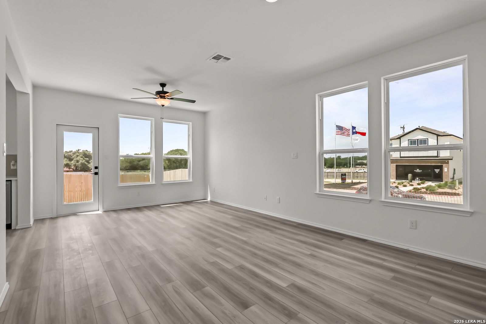 Bright living area with wood-look flooring and ceiling fan in The Florence B floor plan at Meadows at Oak Creek, San Antonio.