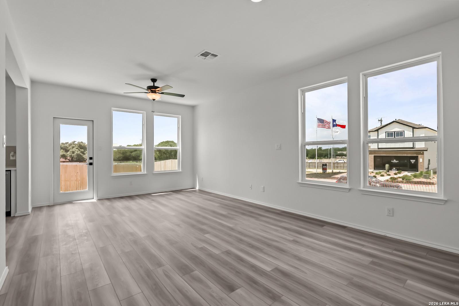 Bright living area with wood-look flooring and ceiling fan in The Florence B floor plan at Meadows at Oak Creek, San Antonio.