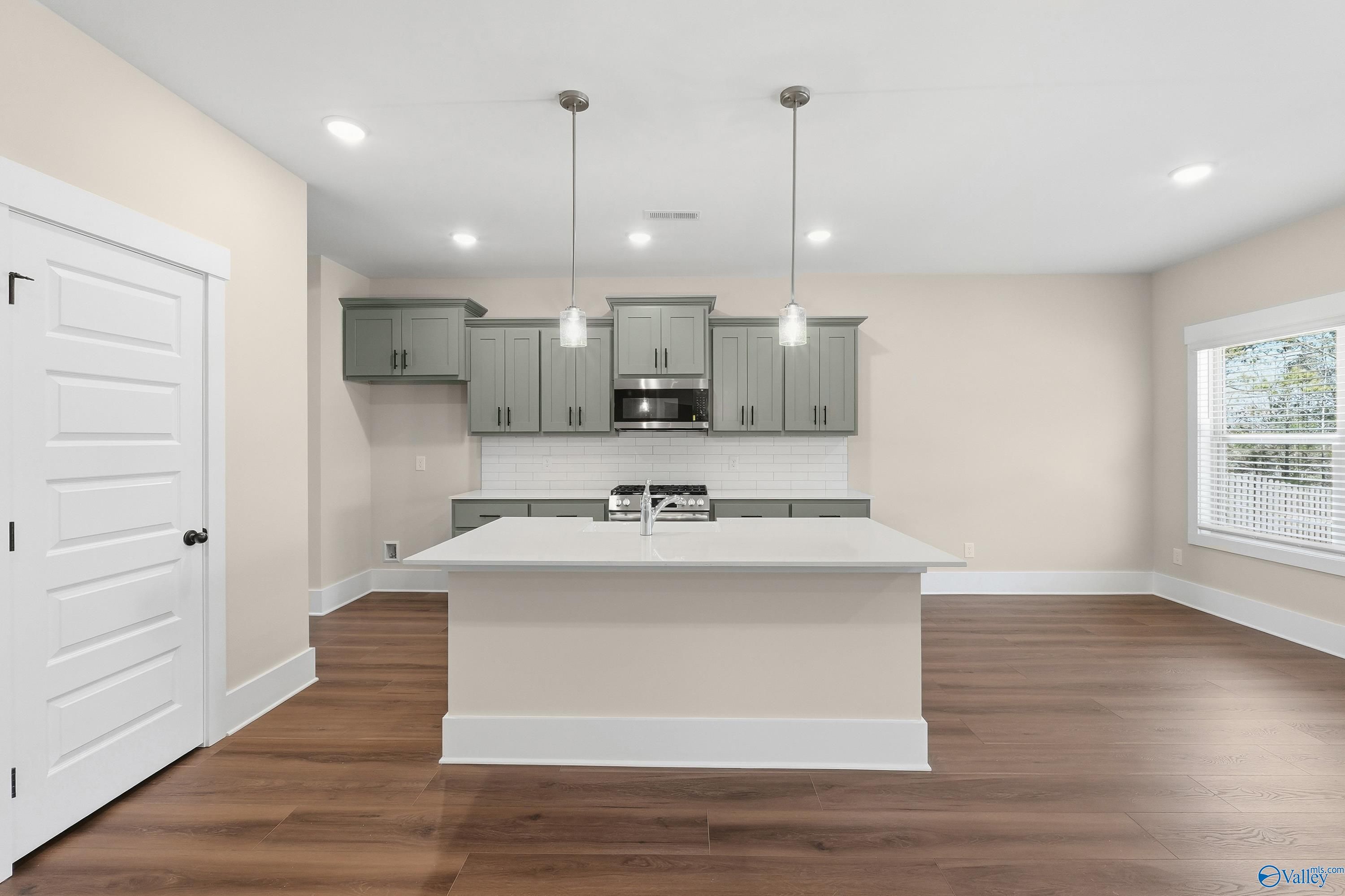Modern kitchen featuring gray shaker cabinets, white subway tile backsplash, and center island sink in Davidson Homes The Shelby A, Athens, Alabama