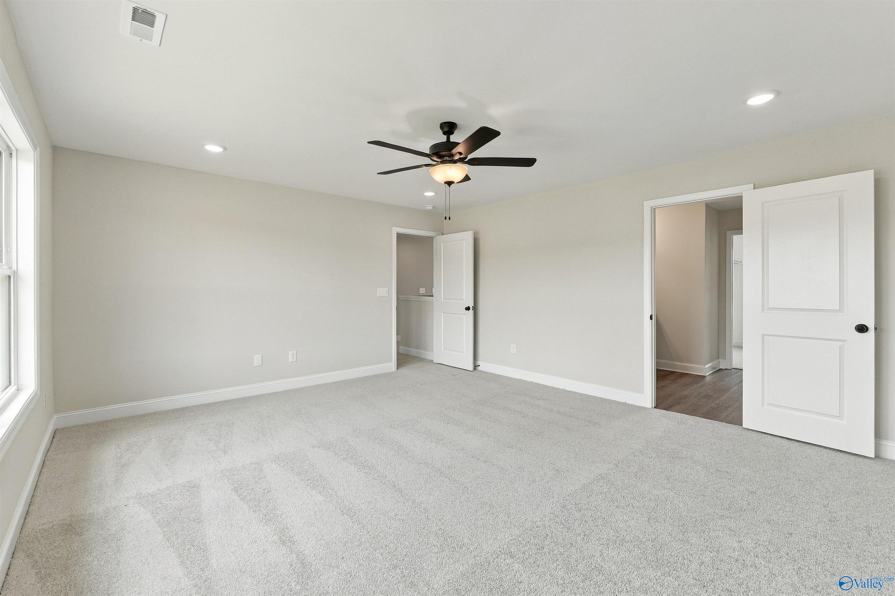 Spacious carpeted bedroom with ceiling fan and recessed lighting in Davidson Homes The Shelby A, The Meadows, Athens, Alabama