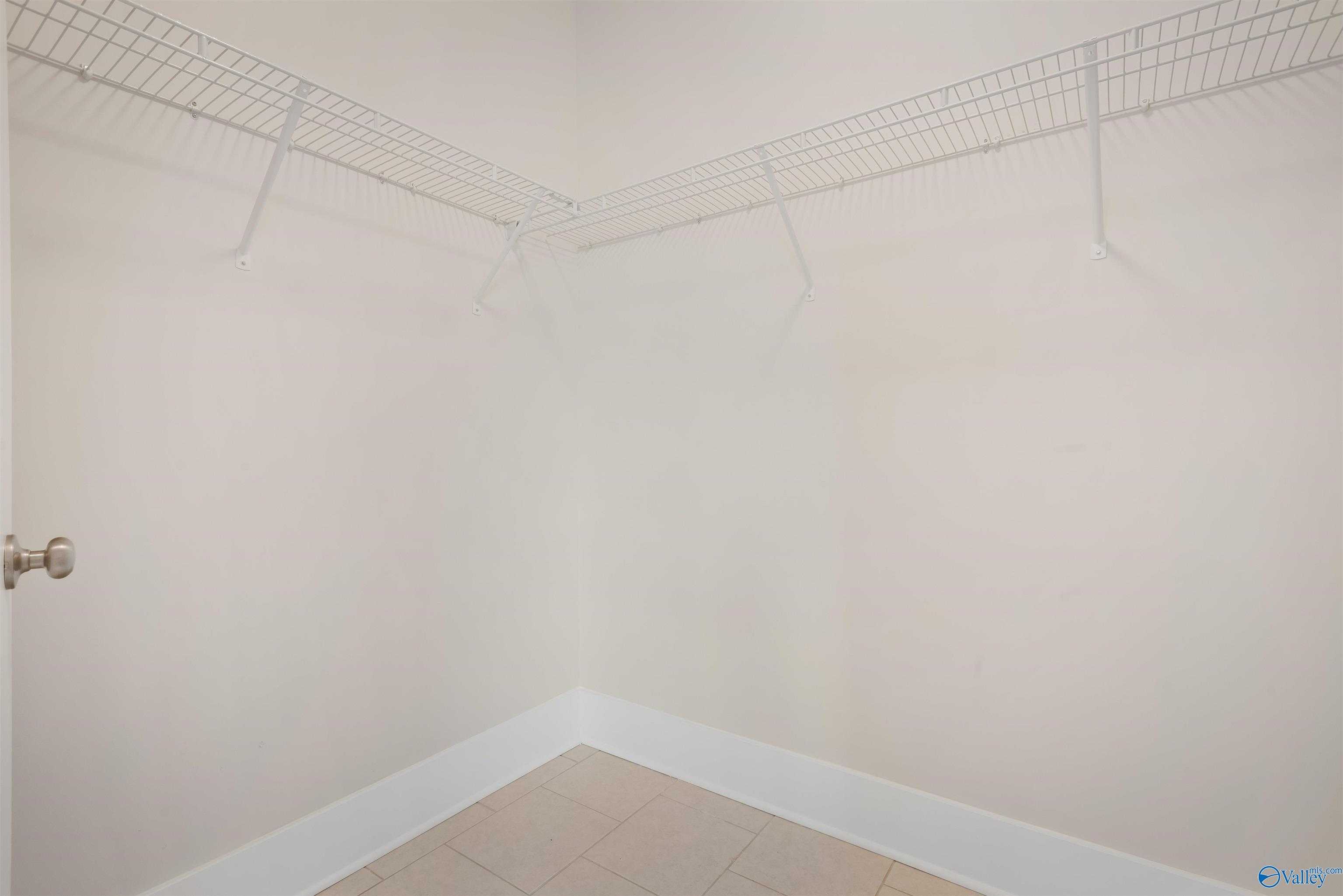 Spacious corner walk-in closet with wire shelving and beige walls in Davidson Homes The Daphne master suite, Harvest AL