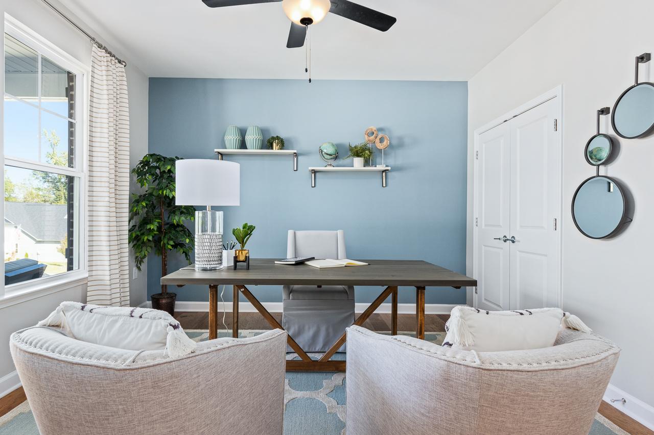 Cozy home office in Prince Place, Fuquay-Varina NC with wooden desk, blue accent wall, potted plants, ceiling fan and lounge chairs