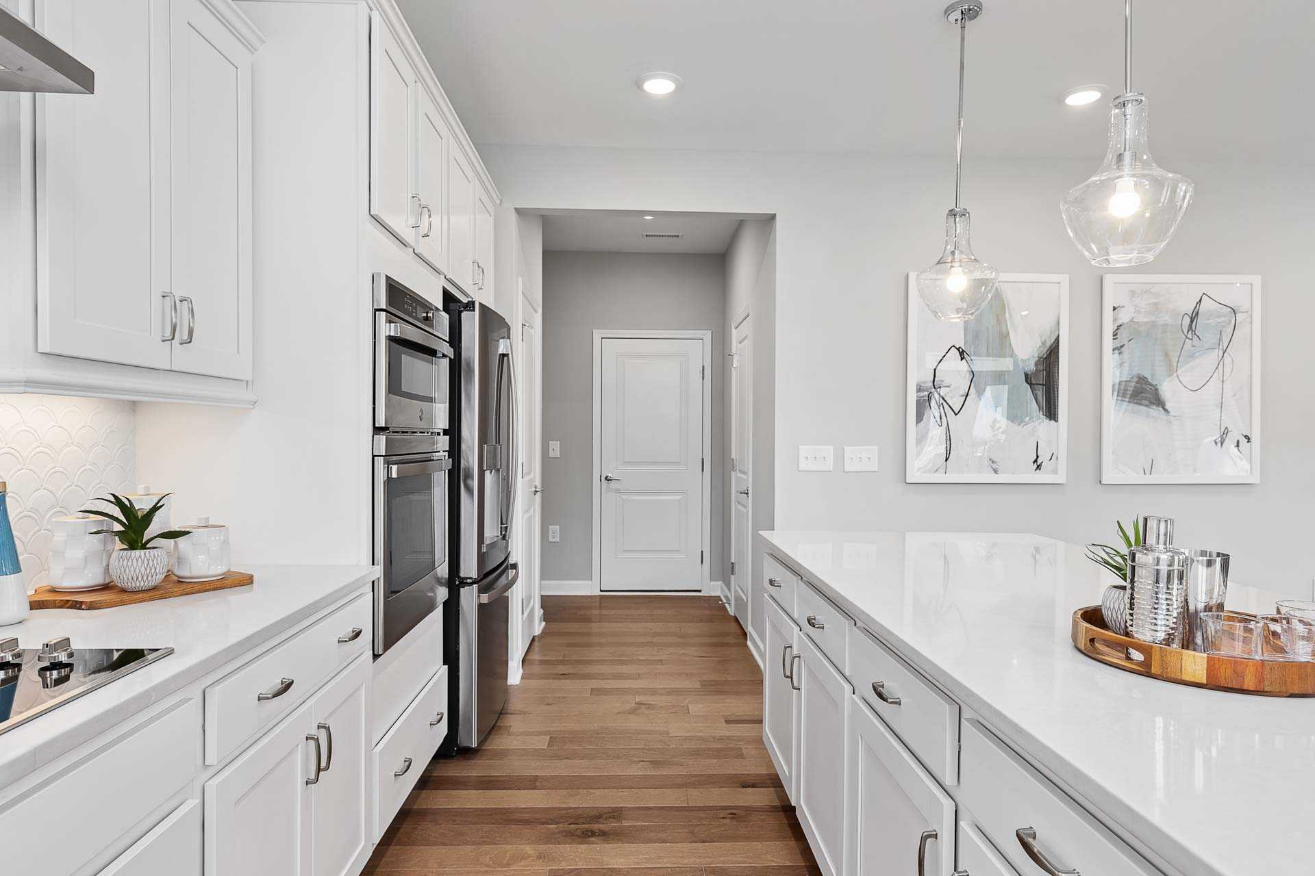Bright white shaker kitchen with quartz island, stainless appliances, hardwood floors at Highland Forest, Fuquay-Varina NC