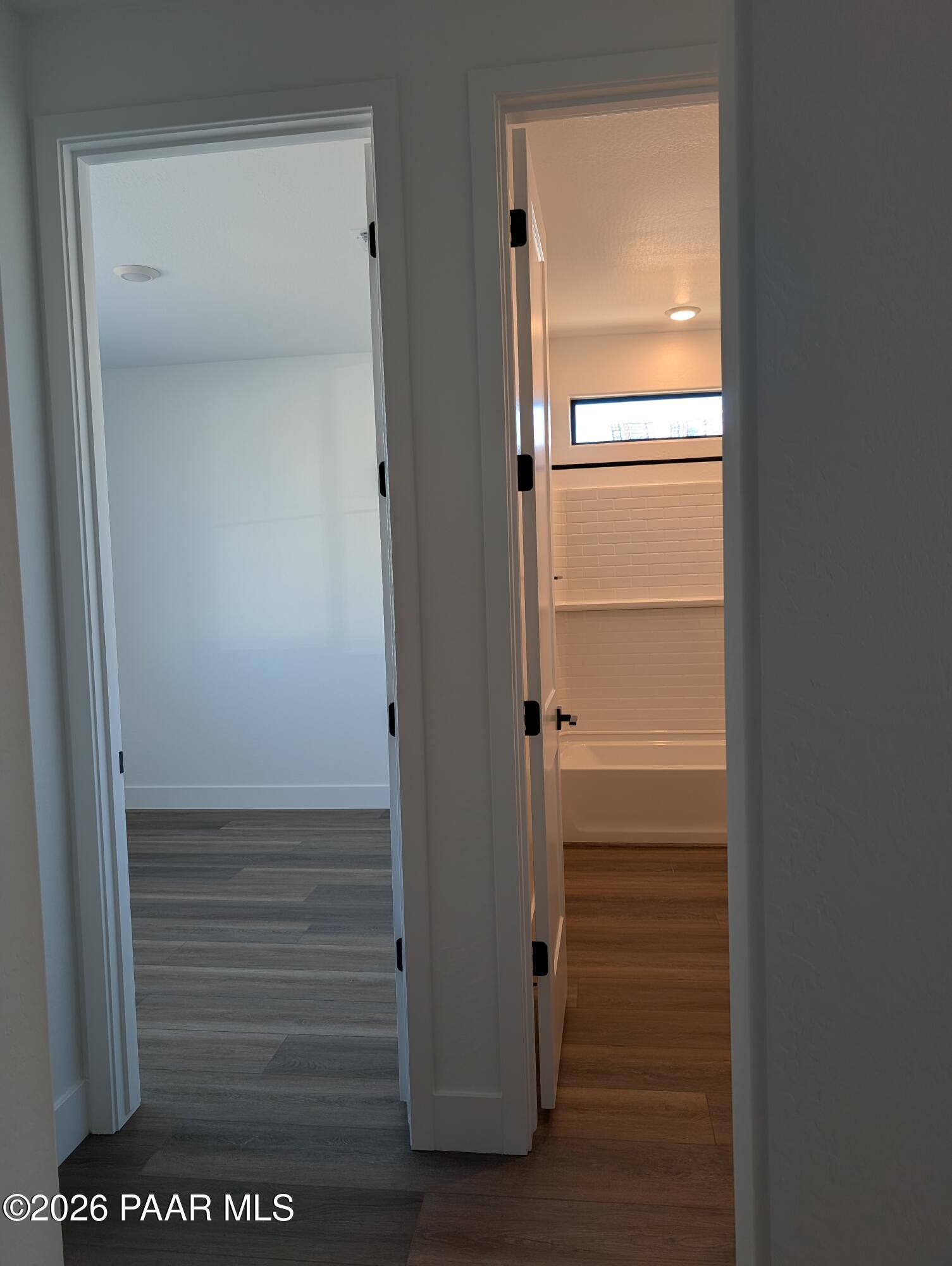 Modern bathroom with white subway tile shower, deep soaking tub, and laminate flooring in The Sheridan II G, Prescott, Arizona