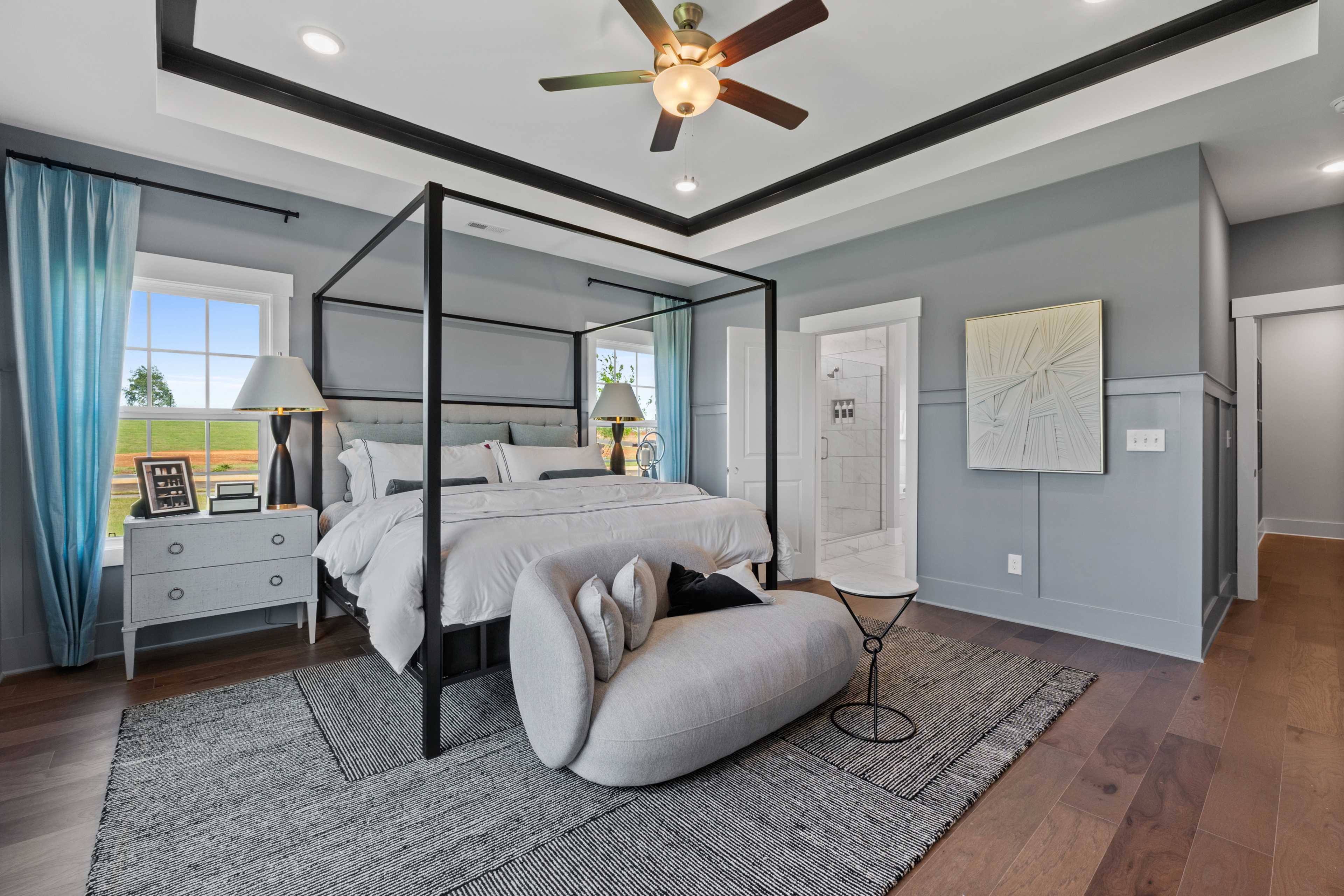 Spacious master bedroom in Creekside, Harvest AL with canopy king bed, gray walls, ceiling fan, and hardwood floors