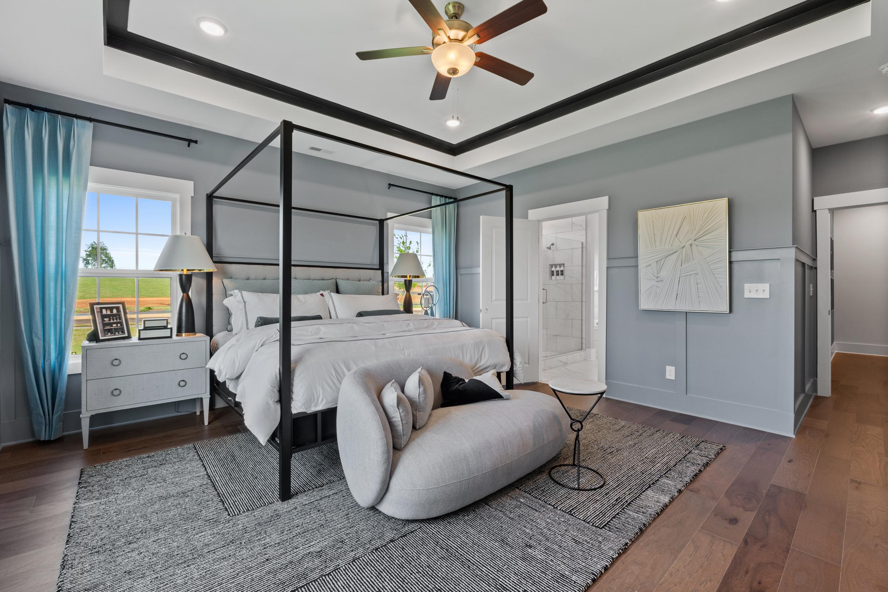 Spacious master bedroom in Creekside, Harvest AL with canopy king bed, gray walls, ceiling fan, and hardwood floors
