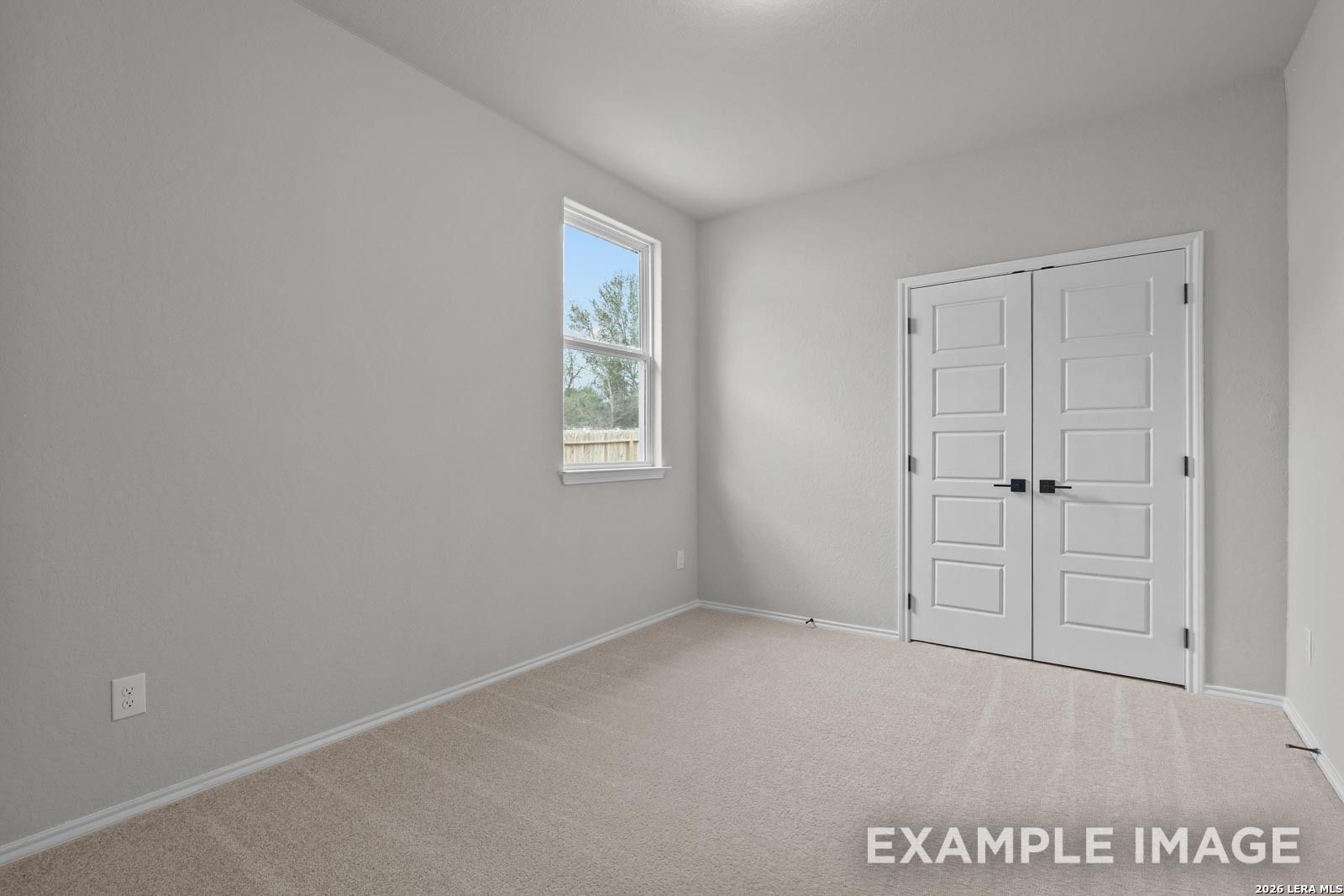 Bright bedroom with neutral walls, plush carpeting, and double-door closet in The Glenwood E by Davidson Homes, San Antonio.
