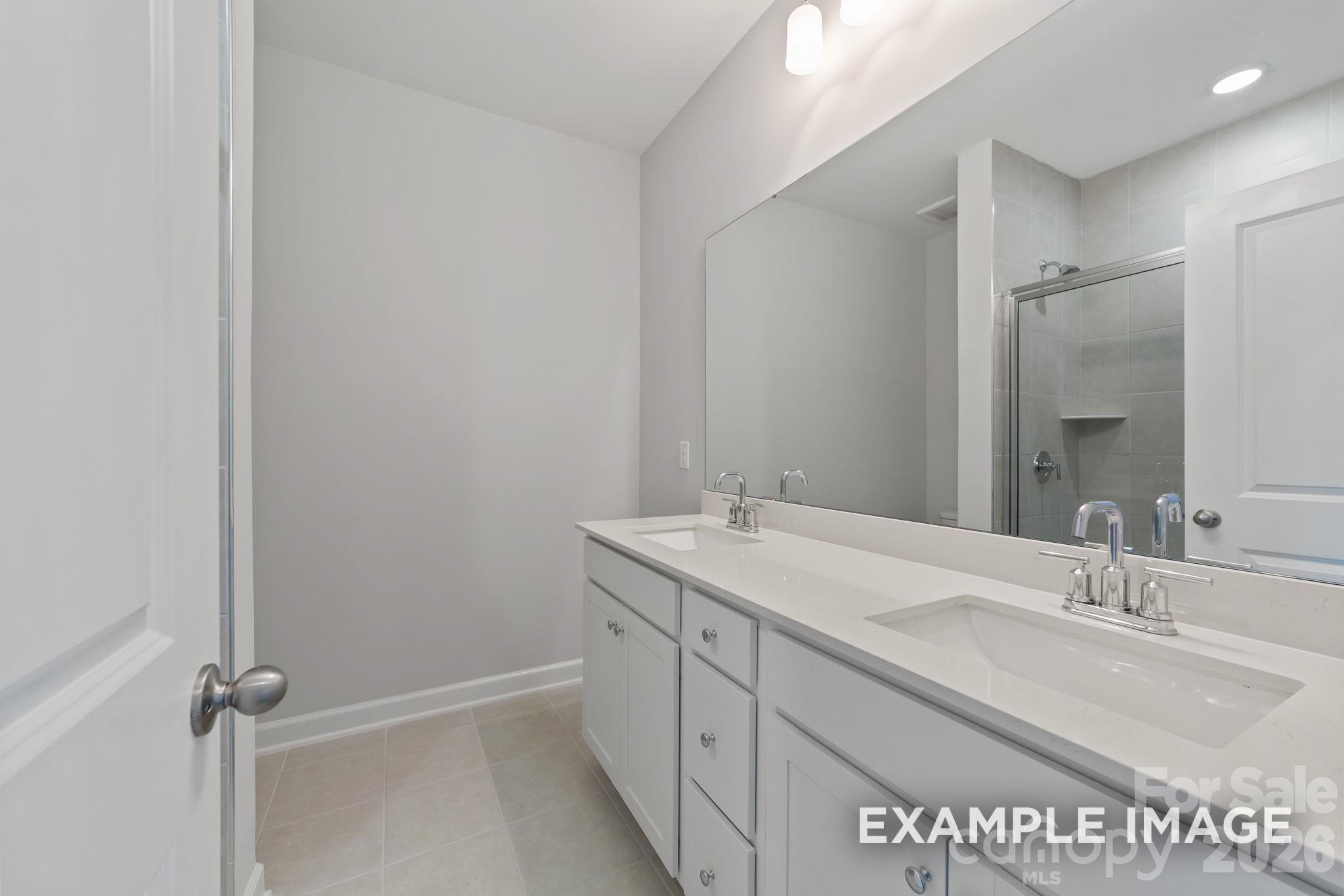 Modern bathroom with double vanity, quartz countertops, and walk-in shower in The Magnolia B at Windgate, Mooresville, NC.