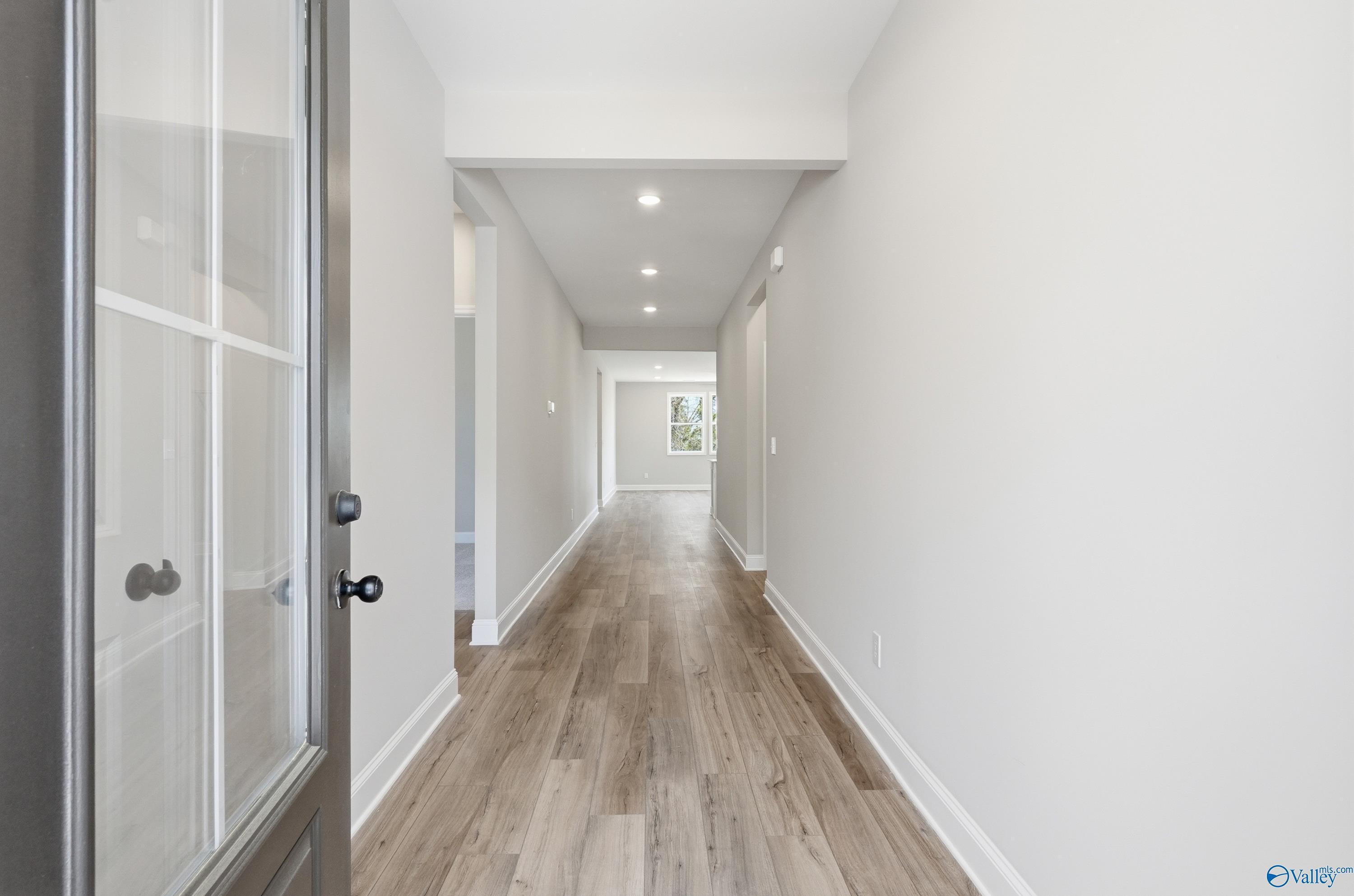 Welcoming entry hallway with light wood floors, recessed lights, and white walls in Davidson Homes The Laurel K, Cullman, Alabama