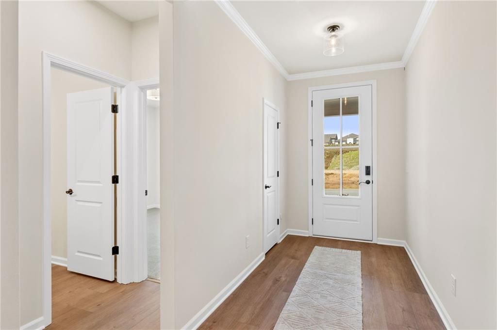 Welcoming entry foyer with hardwood floors, white doors, and glass-front entry in The Daphne B, Kelly Preserve, Loganville, GA
