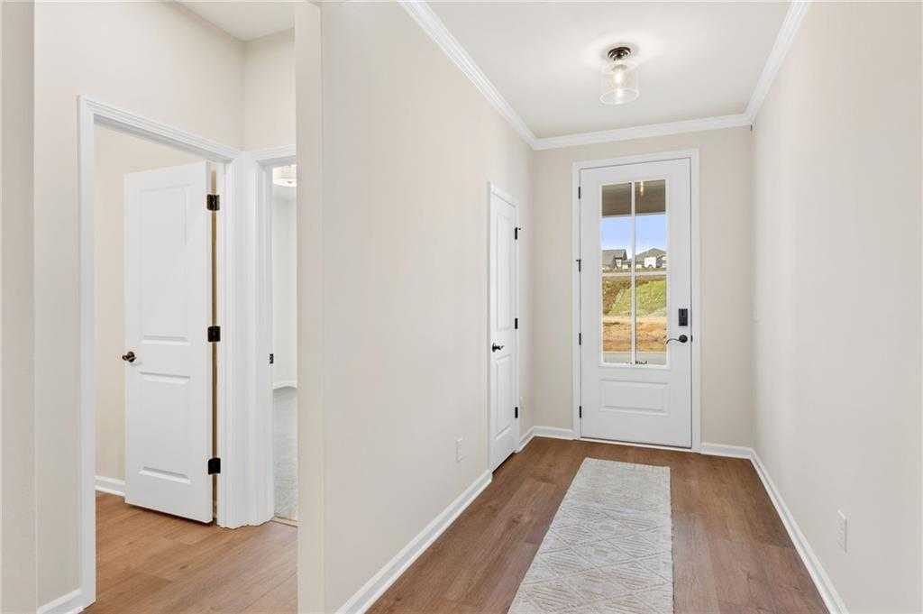 Welcoming entry foyer with hardwood floors, white doors, and glass-front entry in The Daphne B, Kelly Preserve, Loganville, GA