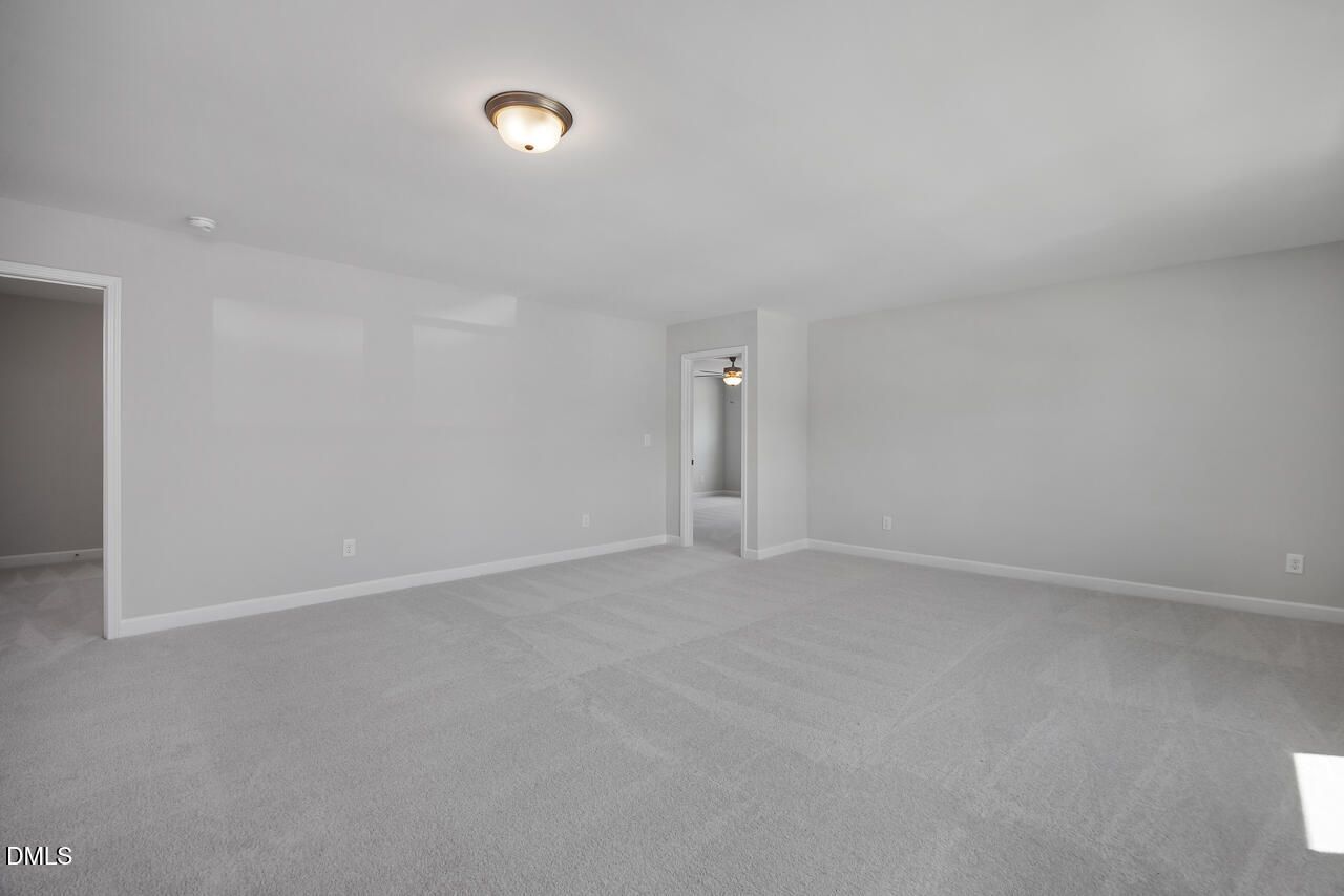 Spacious, neutral-toned carpeted bedroom in The Adalynn B floor plan at Gregory Village in Lillington, North Carolina.