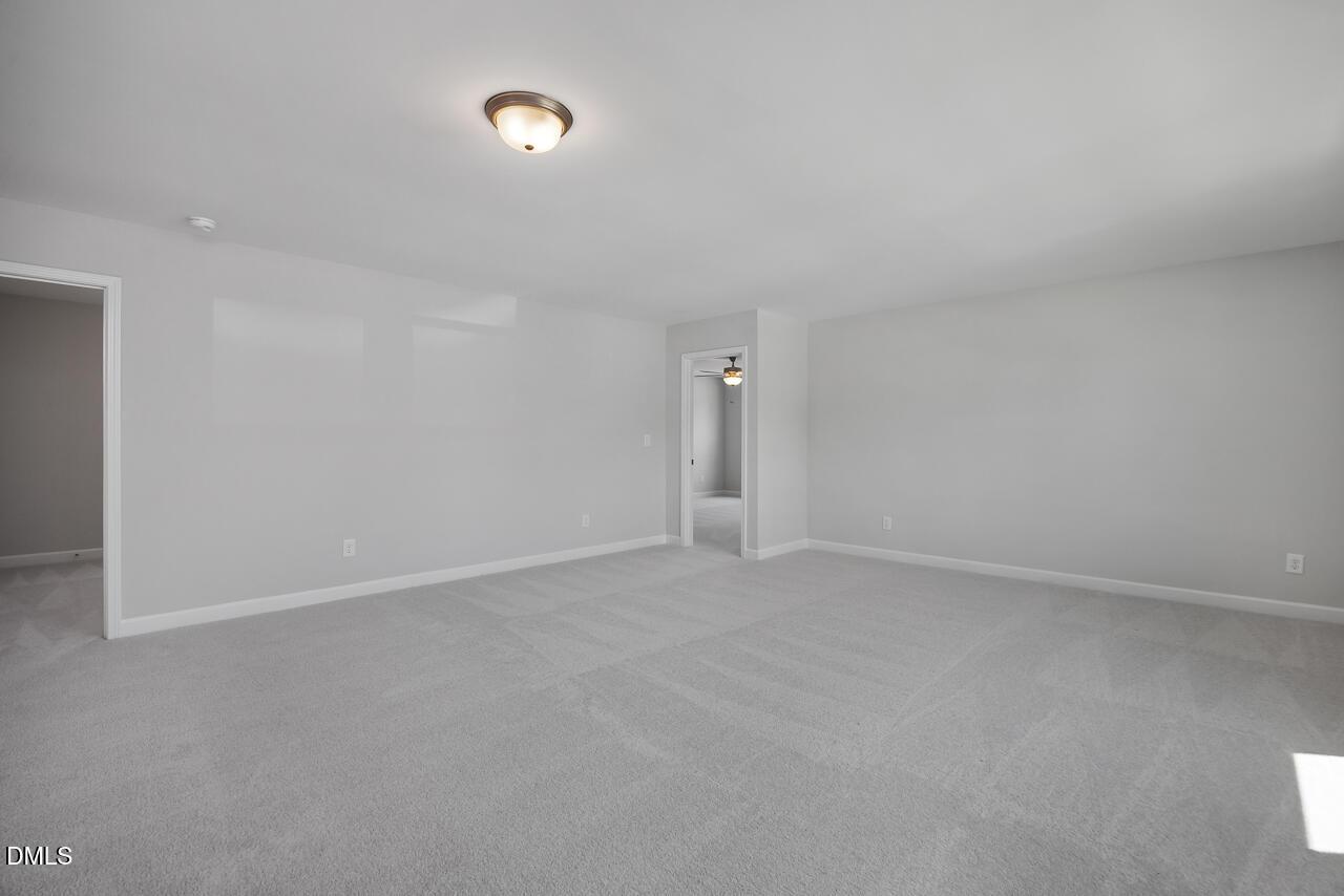 Spacious, neutral-toned carpeted bedroom in The Adalynn B floor plan at Gregory Village in Lillington, North Carolina.