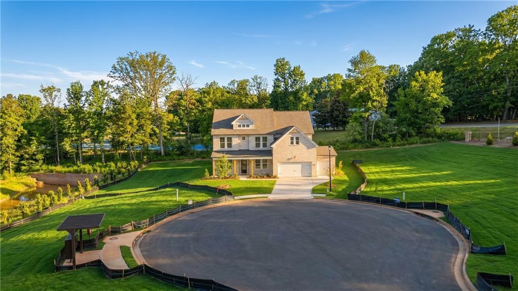 Two-story Danbury C home by Davidson Homes in Melody Lakeside Estates, Buford, GA, with 3-car garage, circular driveway, pond, and lush trees