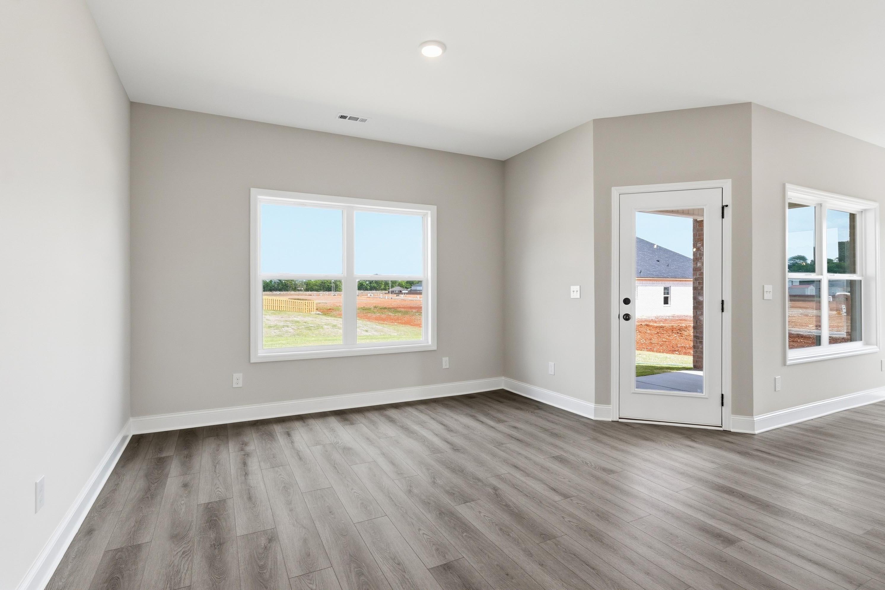 Bright, open-concept living area in The Glen A floor plan with luxury vinyl plank flooring and access to back patio.