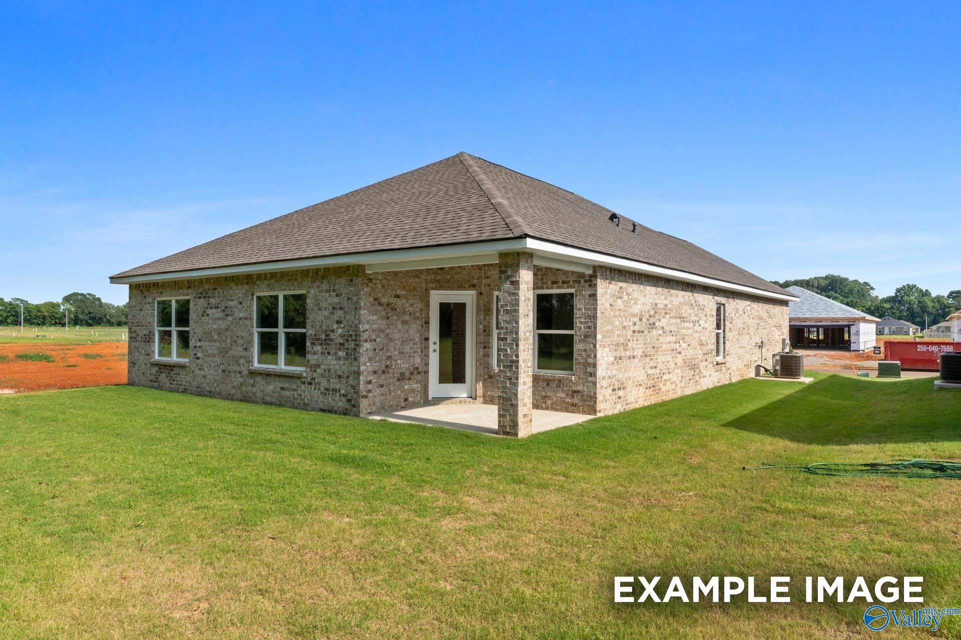 Single-story brick home with gabled roof, covered porch, and lush green yard in The Highlands, Arab, Alabama