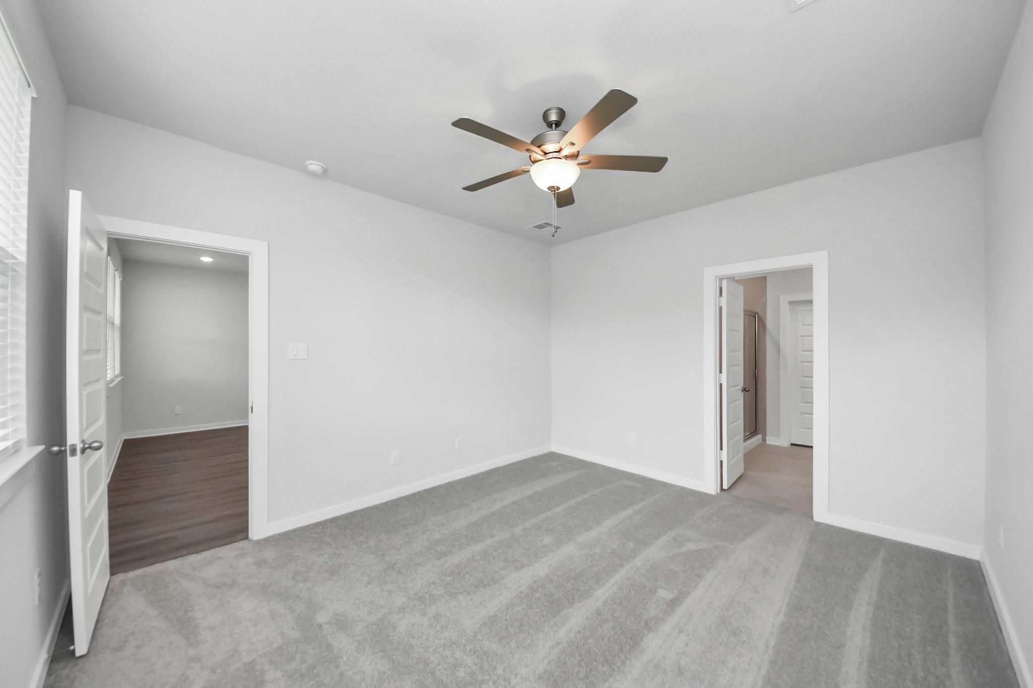 Bright, carpeted bedroom with ceiling fan in The Brazos F floor plan by Davidson Homes at Liberty Estates, Cleveland, TX.