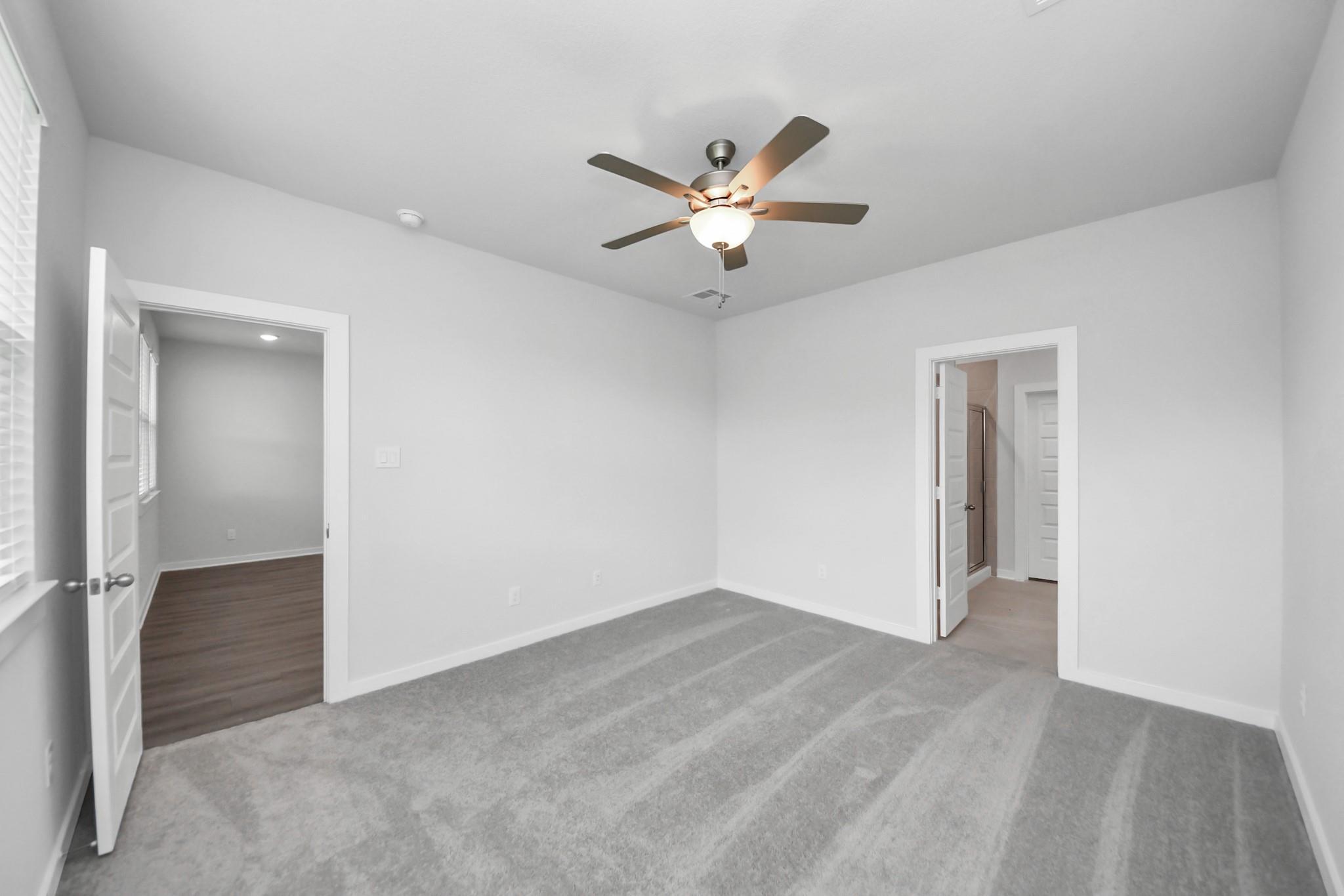 Bright, carpeted bedroom with ceiling fan in The Brazos F floor plan by Davidson Homes at Liberty Estates, Cleveland, TX.