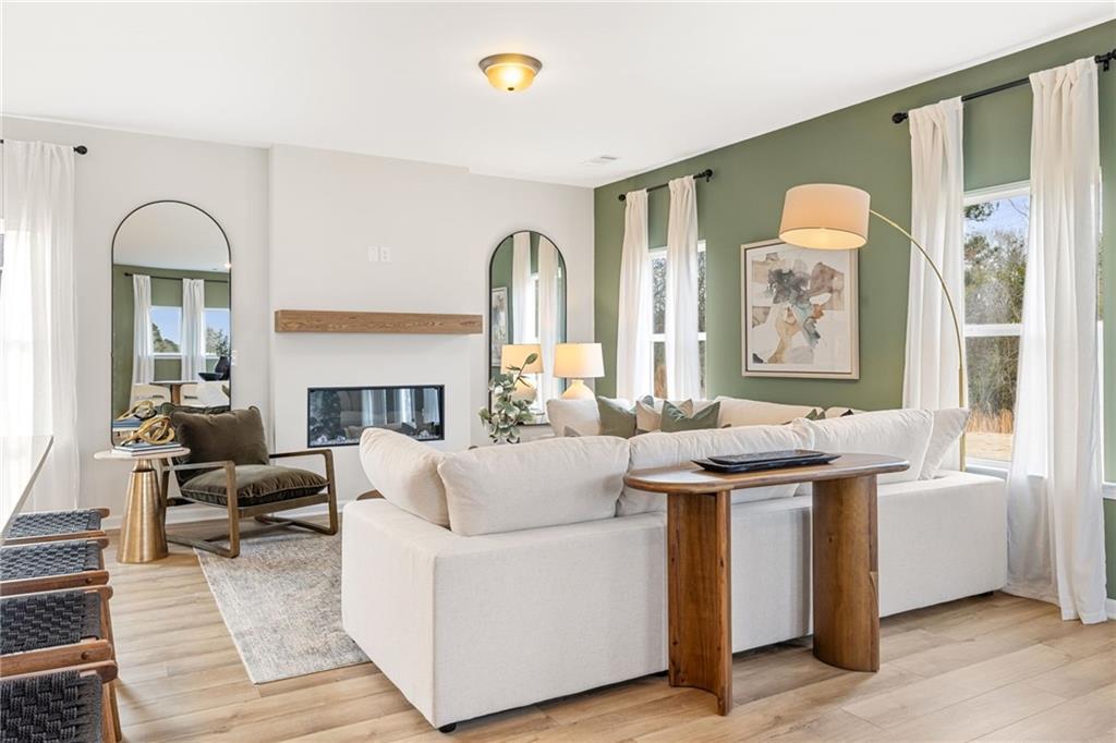 Modern living room with fireplace and sage green accent wall in The Rabun B floor plan at The Bluffs in Canton, Georgia.