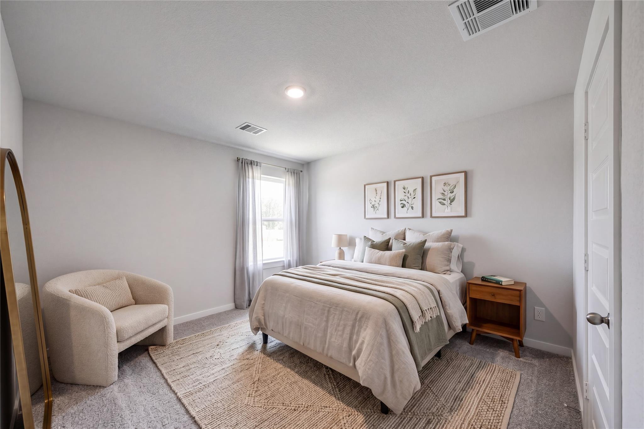 Bright neutral bedroom with plush bedding, accent chair, and botanical wall art in Davidson Homes Sabine F plan, Cleveland, TX