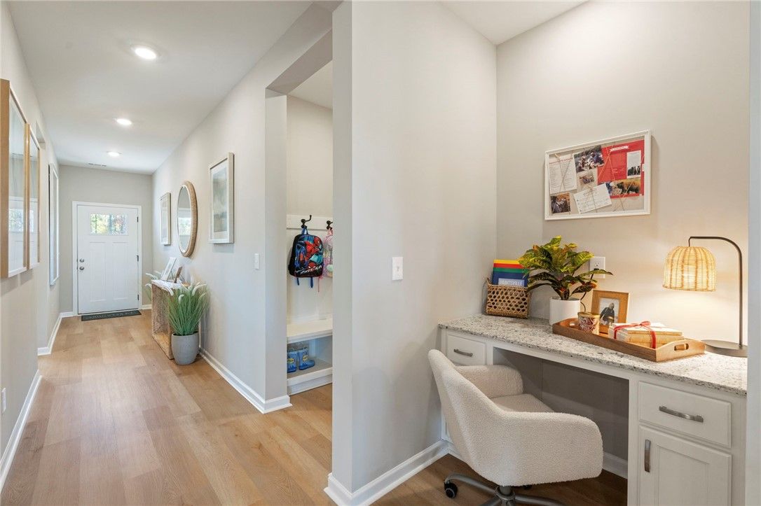 Entry hallway with coat hooks, bench, potted plants, and adjacent home office nook in Davidson Homes The Phoenix B, Opelika, Alabama