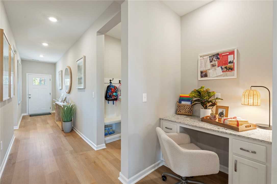 Entry hallway with coat hooks, bench, potted plants, and adjacent home office nook in Davidson Homes The Phoenix B, Opelika, Alabama