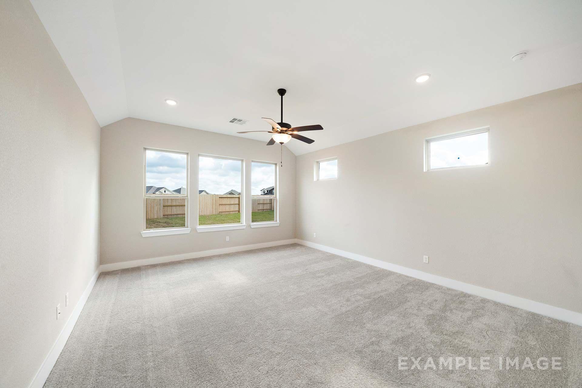 Spacious master suite in The Elizabeth by Davidson Homes featuring vaulted ceiling, carpet flooring, and backyard windows