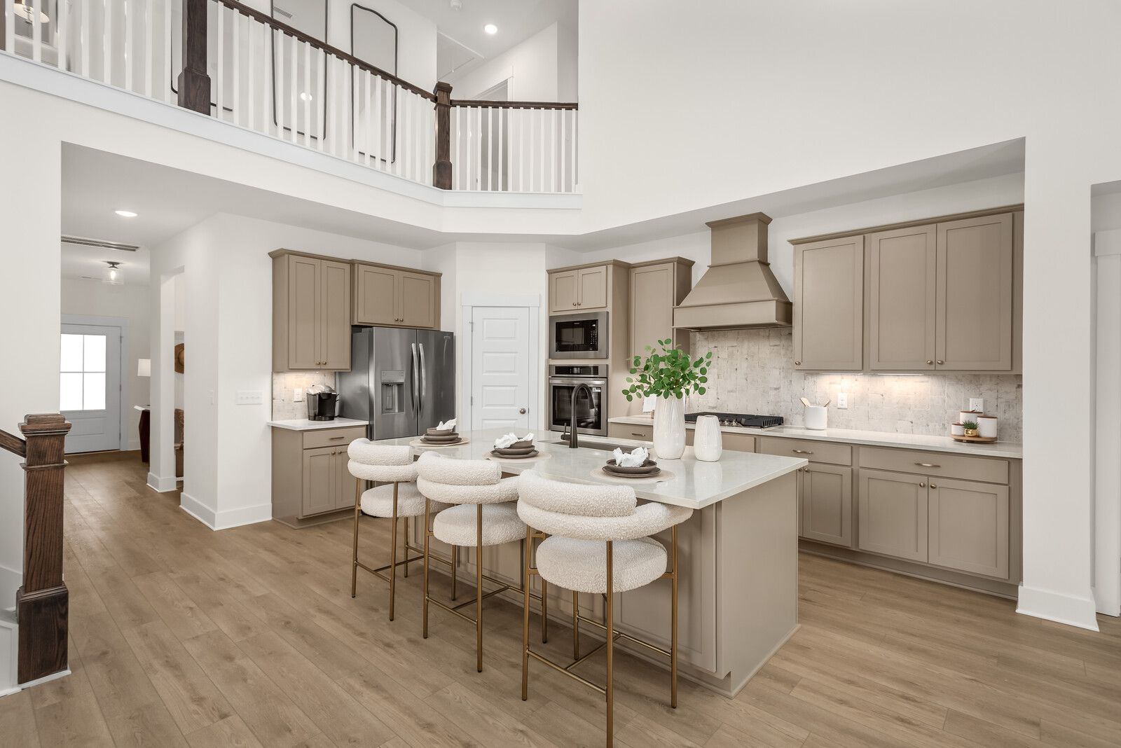 Modern kitchen with quartz island and boucle stools at Benders Cove in Mt. Juliet, Tennessee by Davidson Homes.