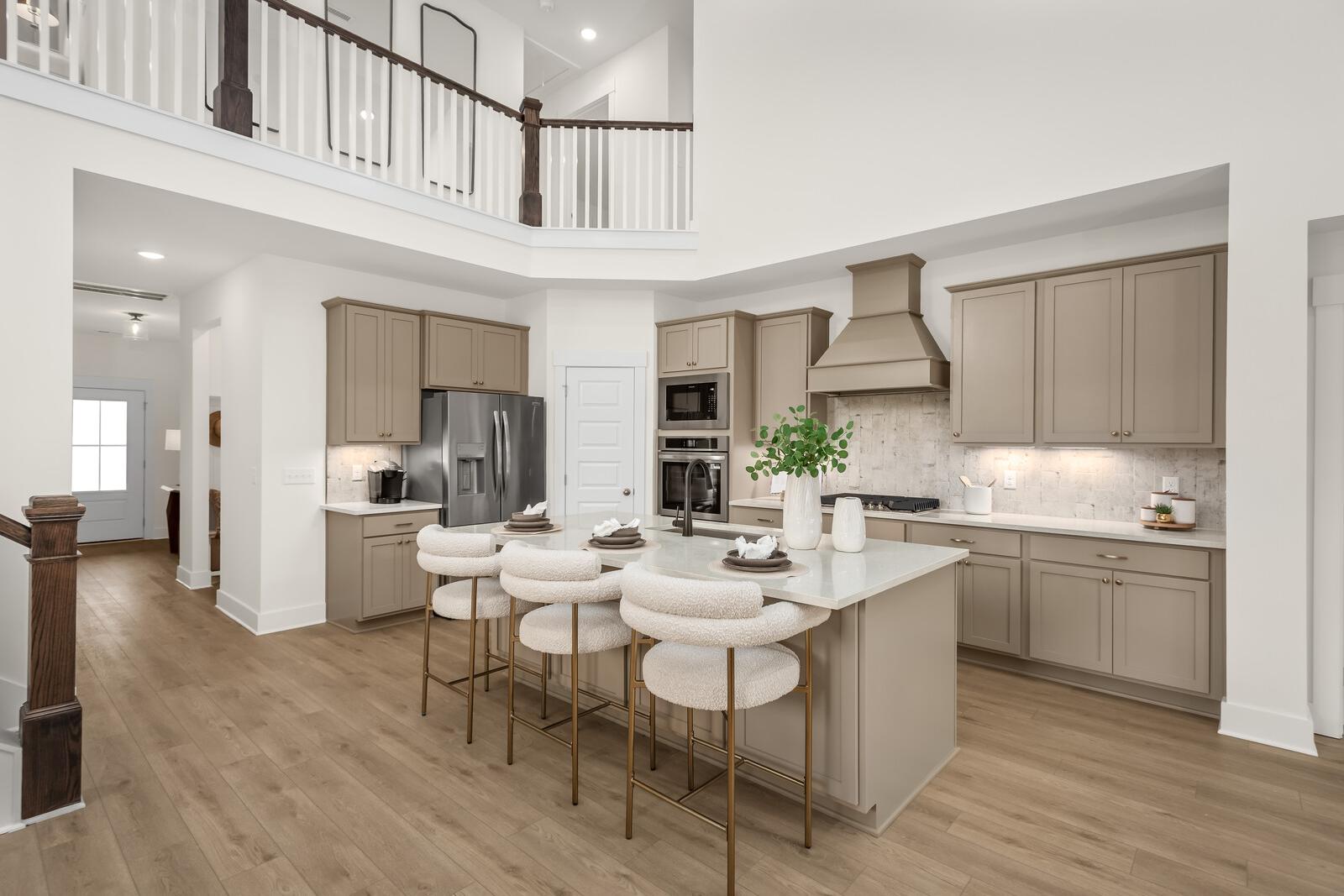 Modern kitchen with quartz island and boucle stools at Benders Cove in Mt. Juliet, Tennessee by Davidson Homes.