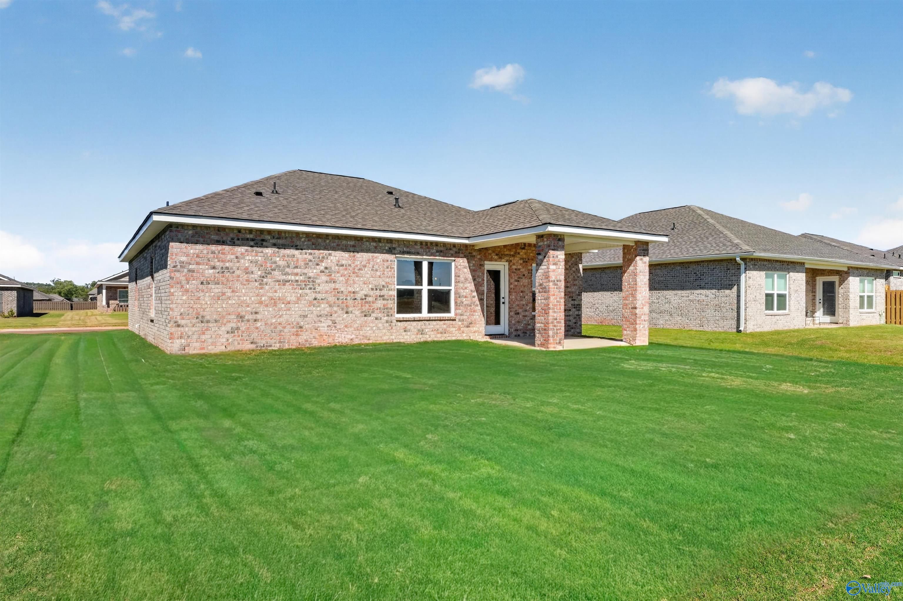Brick single-story home with covered patio and spacious green backyard in Davidson Homes' The Butler plan, Hazel Green, Alabama