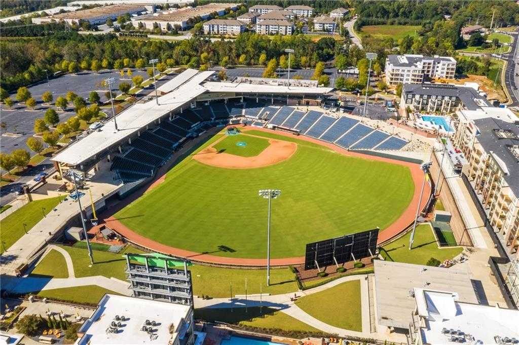 Aerial view of baseball stadium with lush green field, bleachers, and scoreboard amid apartments in Buford, Georgia