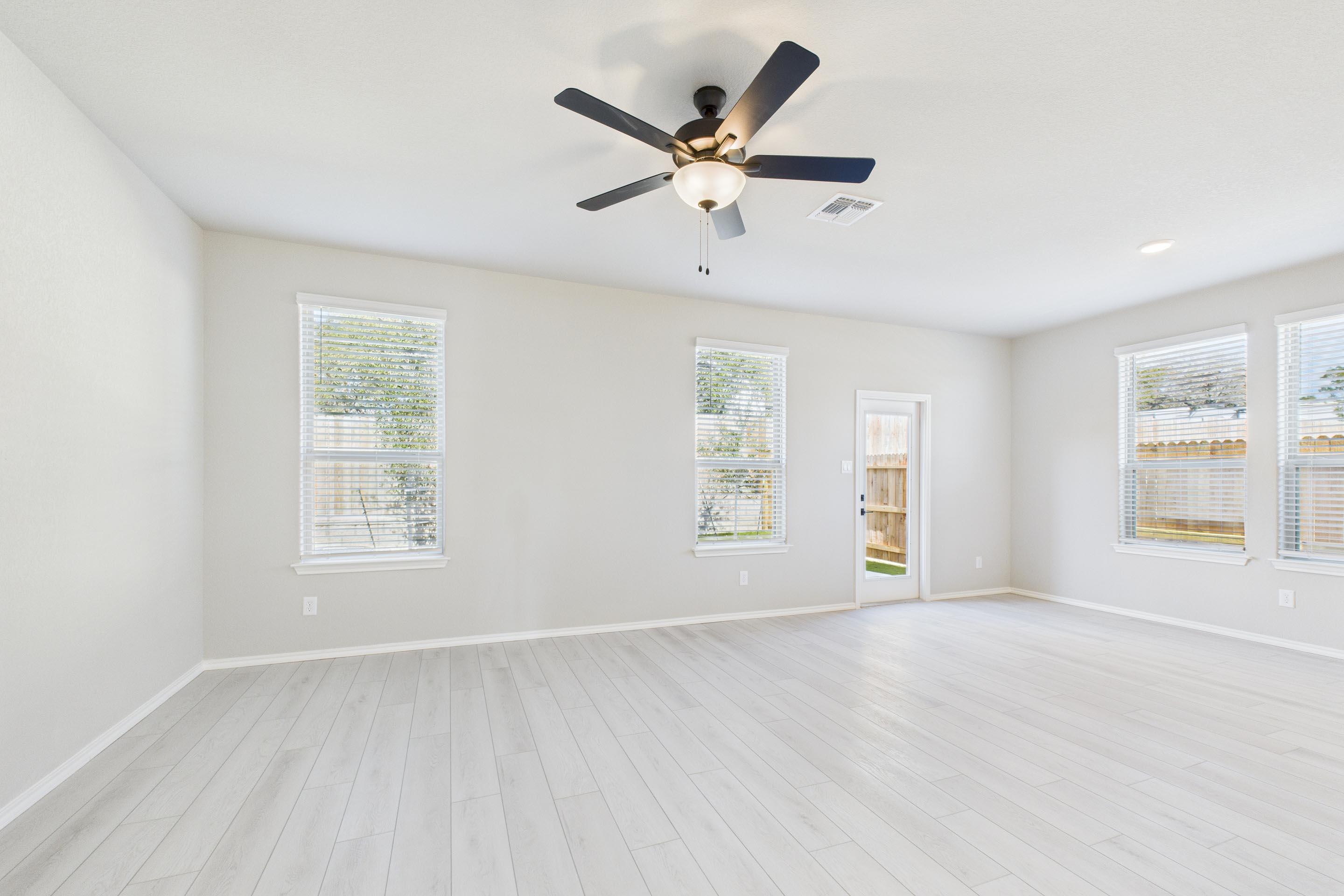 Spacious and bright living area in The Charlotte A by Davidson Homes with wood-look flooring and ceiling fan.