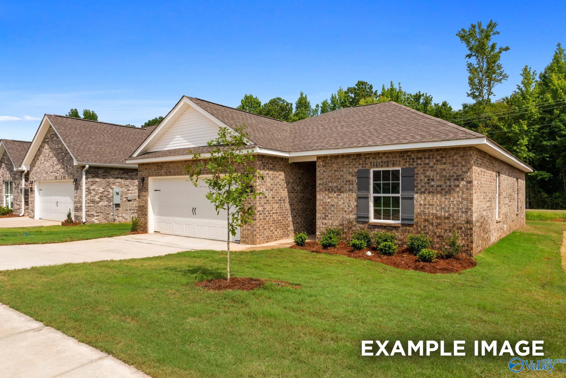 Brick single-story home with 2-car garage, white shutters, and landscaped yard in Wood Trail, Toney, Alabama
