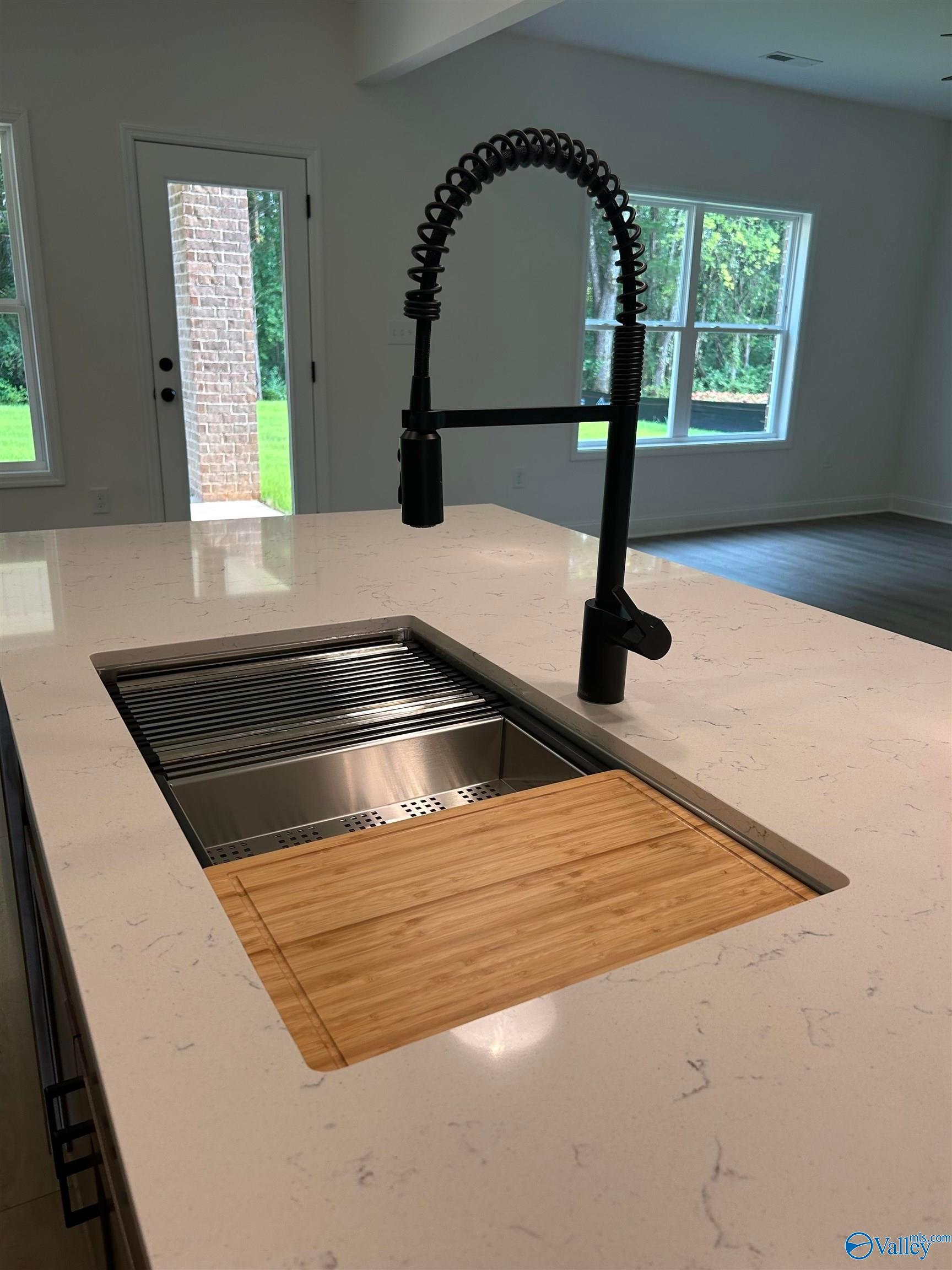 Kitchen island with quartz countertops, workstation sink, and modern faucet in a Shelby B home in Jaguar Hills, Huntsville.