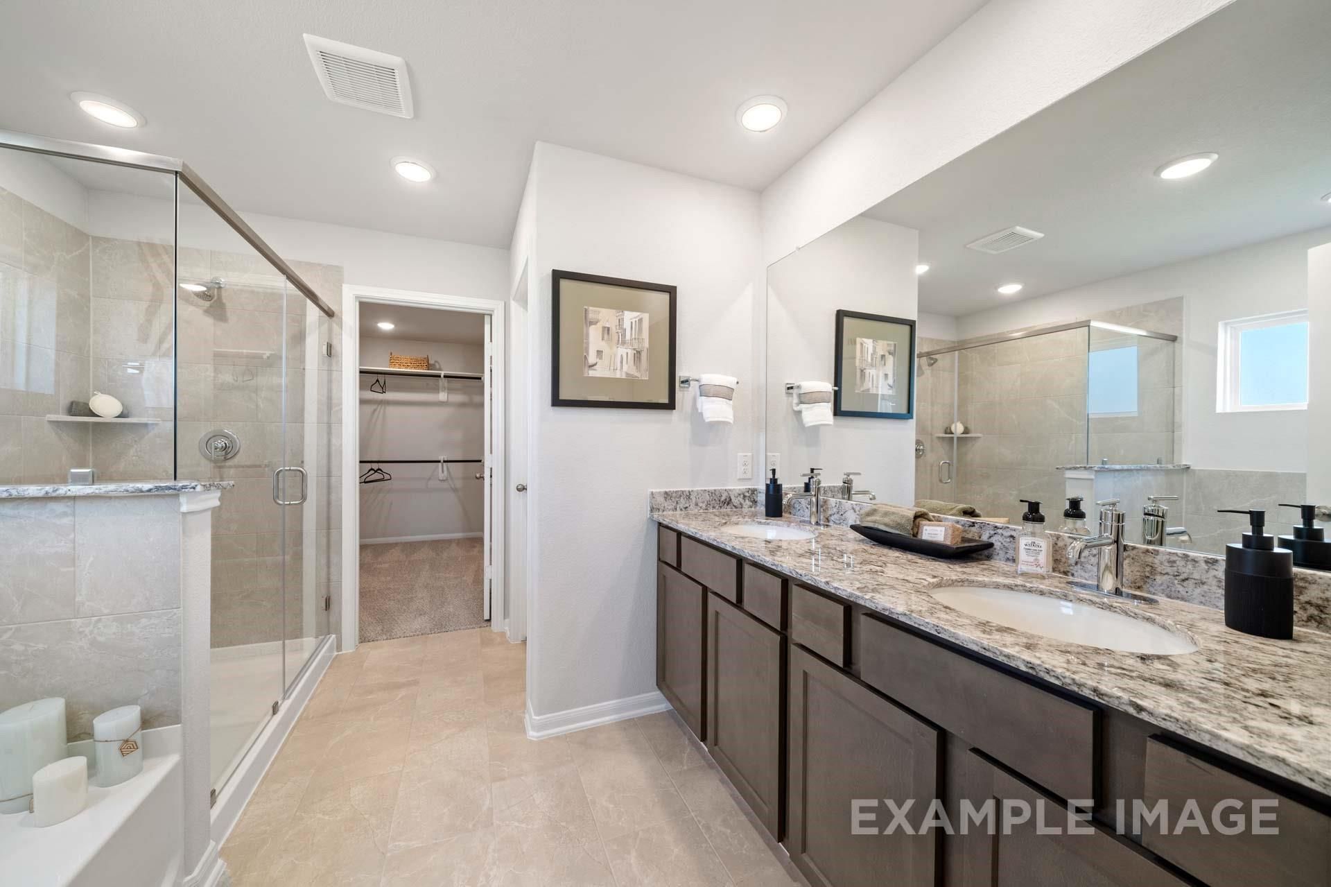 Luxurious master bathroom with double vanity, granite counters, glass shower, and walk-in closet in Davidson Homes Acadia A, Texas City