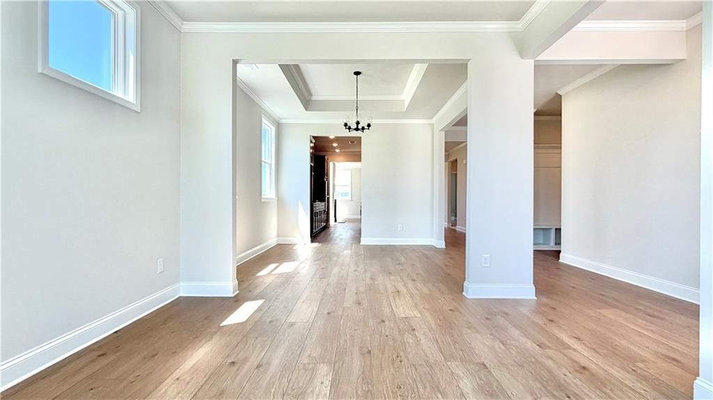 Bright open-concept living area with tray ceiling and hardwood floors in The Glenwood A at Wehunt Meadows, Hoschton, GA.