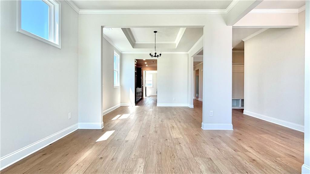 Bright open-concept living area with tray ceiling and hardwood floors in The Glenwood A at Wehunt Meadows, Hoschton, GA.