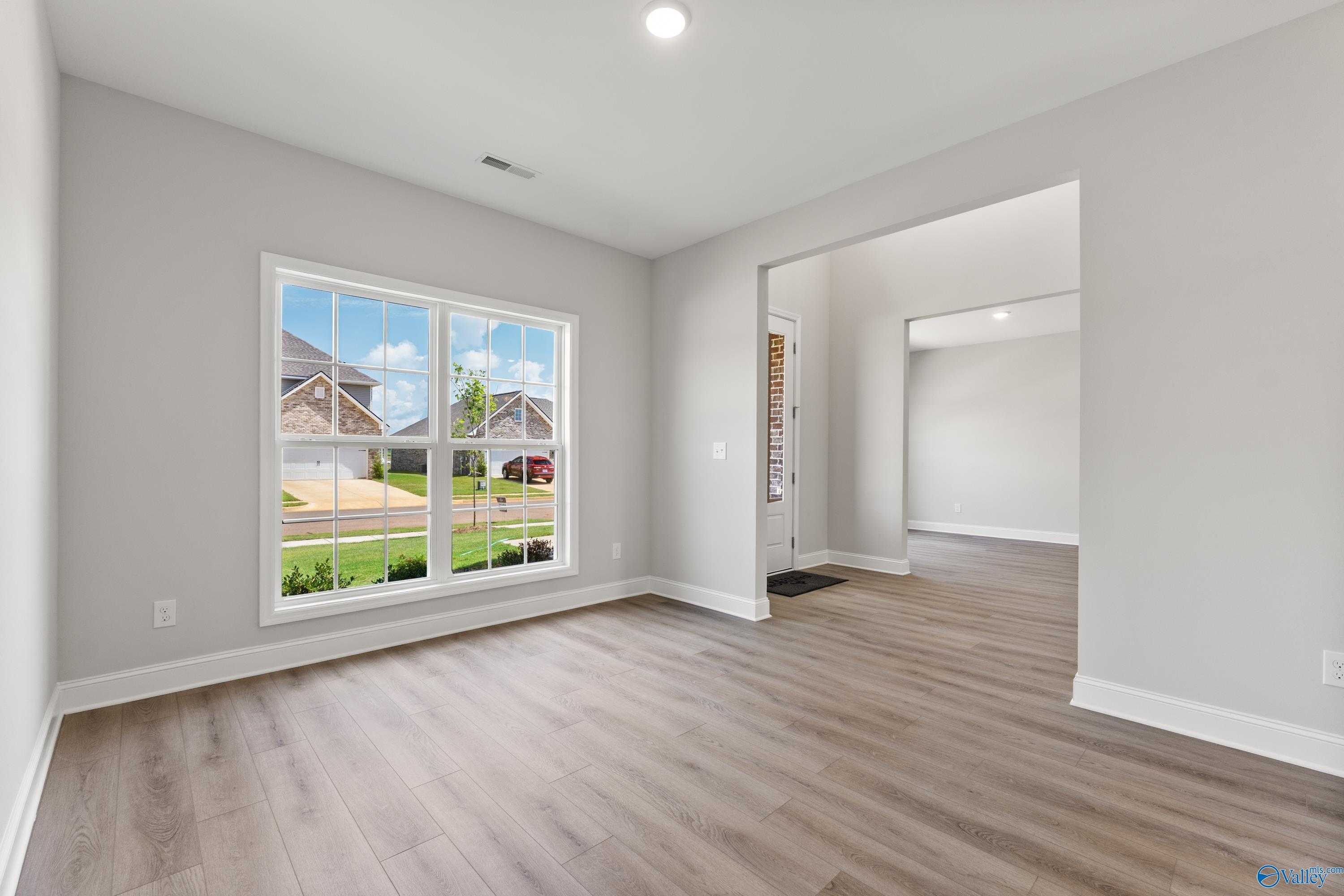 Bright study with light gray walls, hardwood floors, and large windows overlooking neighborhood in Davidson Homes Madison A, Toney AL