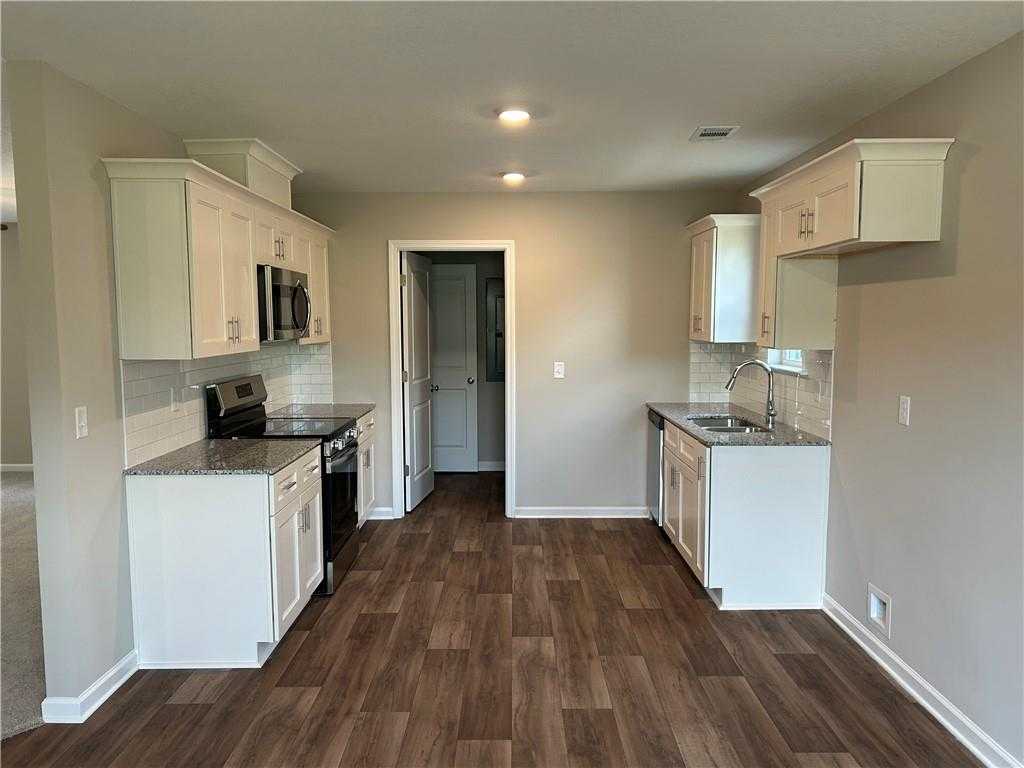 Open-concept kitchen with white shaker cabinets, granite countertops, stainless appliances in Davidson Homes The Washington, Phenix City AL