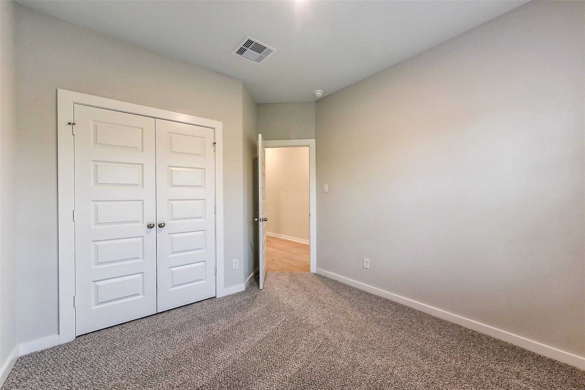 Spacious secondary bedroom with double closet doors and adjacent bath in Davidson Homes The Laguna B, Sunterra, Katy, Texas