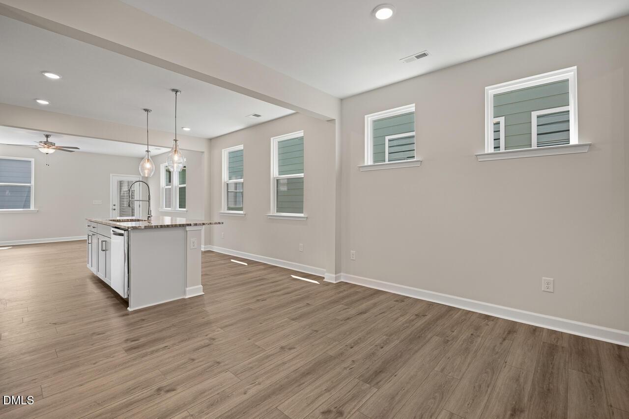 Open-concept kitchen and living area with hardwood floors in The Alexander C home at Forestville Yard, Knightdale, NC.