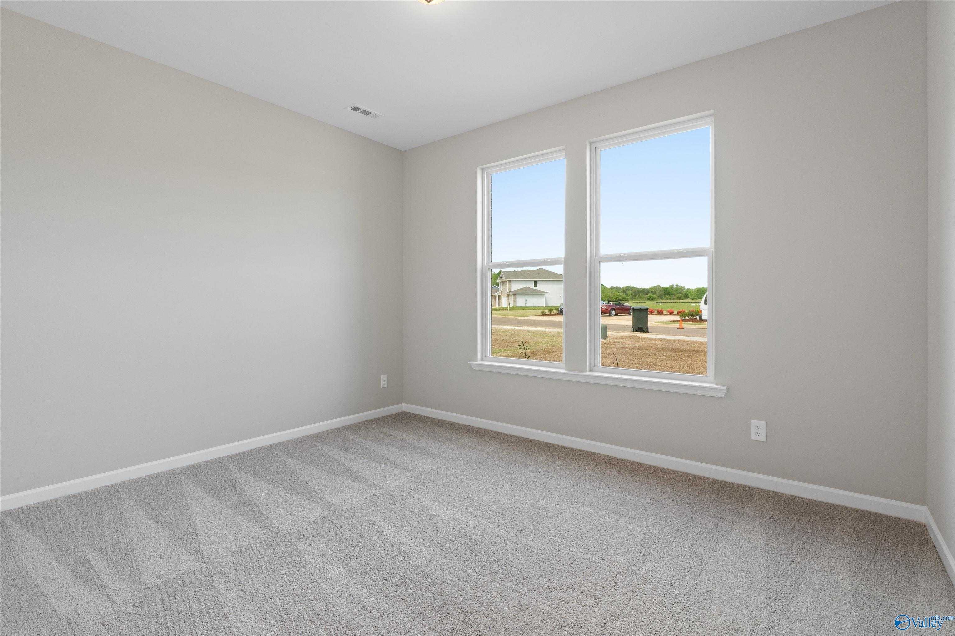 Bright empty bedroom with large windows overlooking neighborhood in The Luna 4-bedroom home, Hazel Green, Alabama