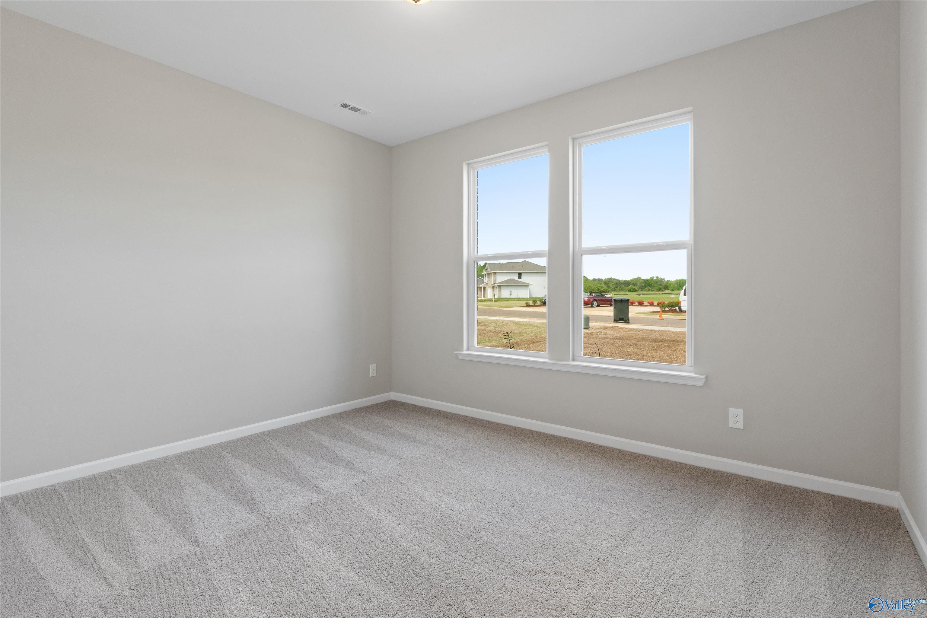 Bright empty bedroom with large windows overlooking neighborhood in The Luna 4-bedroom home, Hazel Green, Alabama