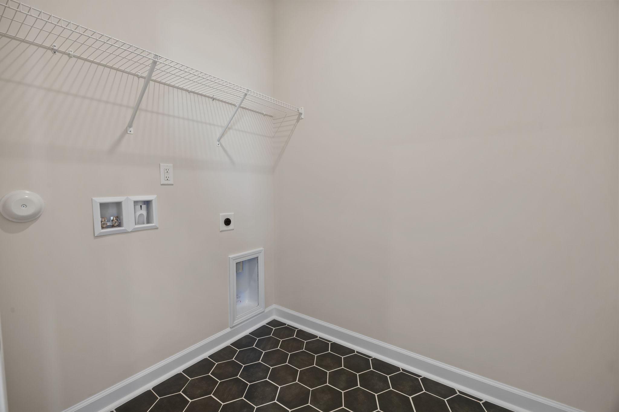 Laundry room with hexagon tile flooring and wire shelving at Forestville Yard in Knightdale, NC by Davidson Homes.