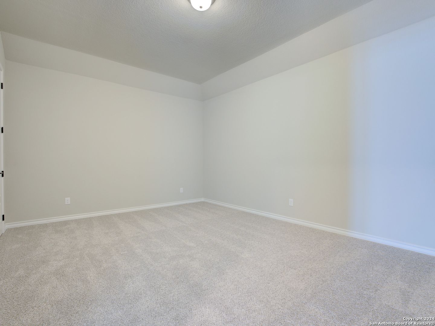 Empty secondary bedroom featuring beige walls, neutral carpet flooring, and bifold closet doors in Davidson Homes The Summerlin A, Castroville, Texas