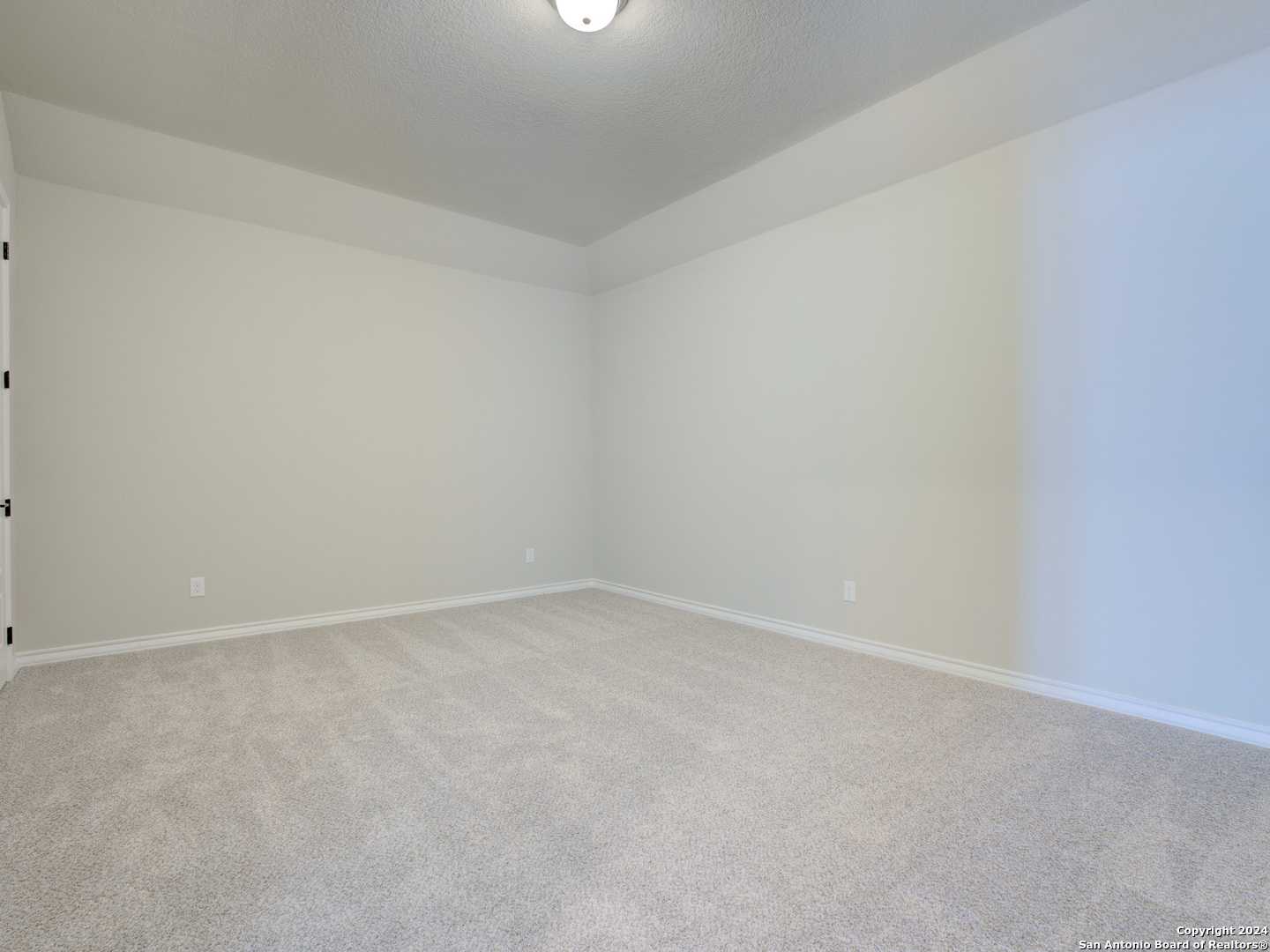 Empty secondary bedroom featuring beige walls, neutral carpet flooring, and bifold closet doors in Davidson Homes The Summerlin A, Castroville, Texas